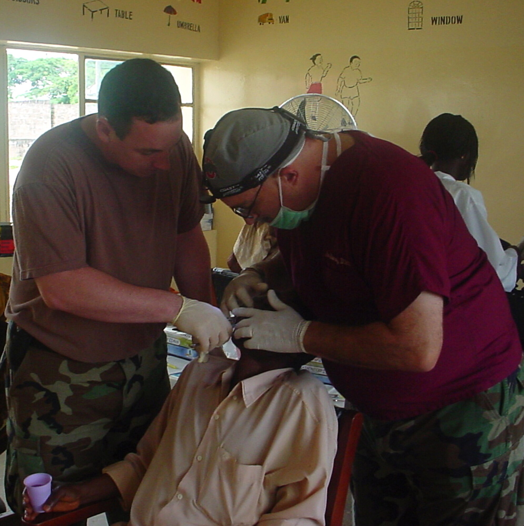 Nigeria -- Air Force Reserve Dentist Maj. (Dr.) Joe Alvarez, right, from the 445th Aerospace Medicine Squadron, Wright-Patterson AFB, Ohio provides dental assistance to a Nigerian civilian with the help from Physicians’ Assistant Capt. Matthew Matocha, left, from Ramstein Air Base, Germany. (U.S. Air Force courtesy photo).