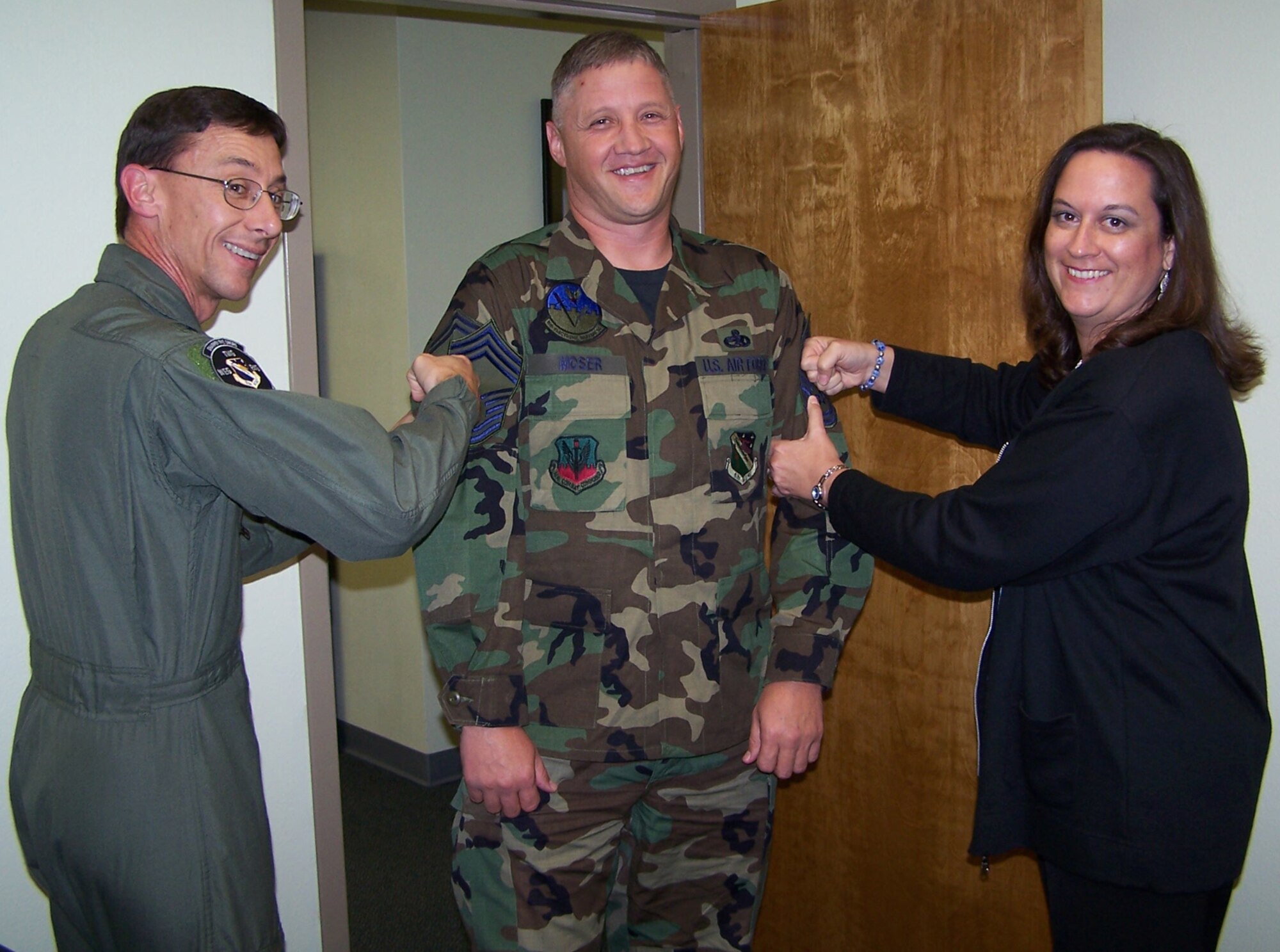 Senior Master Sgt. Neal Moser, 53d Electronic Warfare Group, gets his new chief stripes tacked on by Col. Mark Simpson, 53d Wing vice commander, (left) and his wife Tamara.  (Photo by Master Sgt. Roy Grubbs)