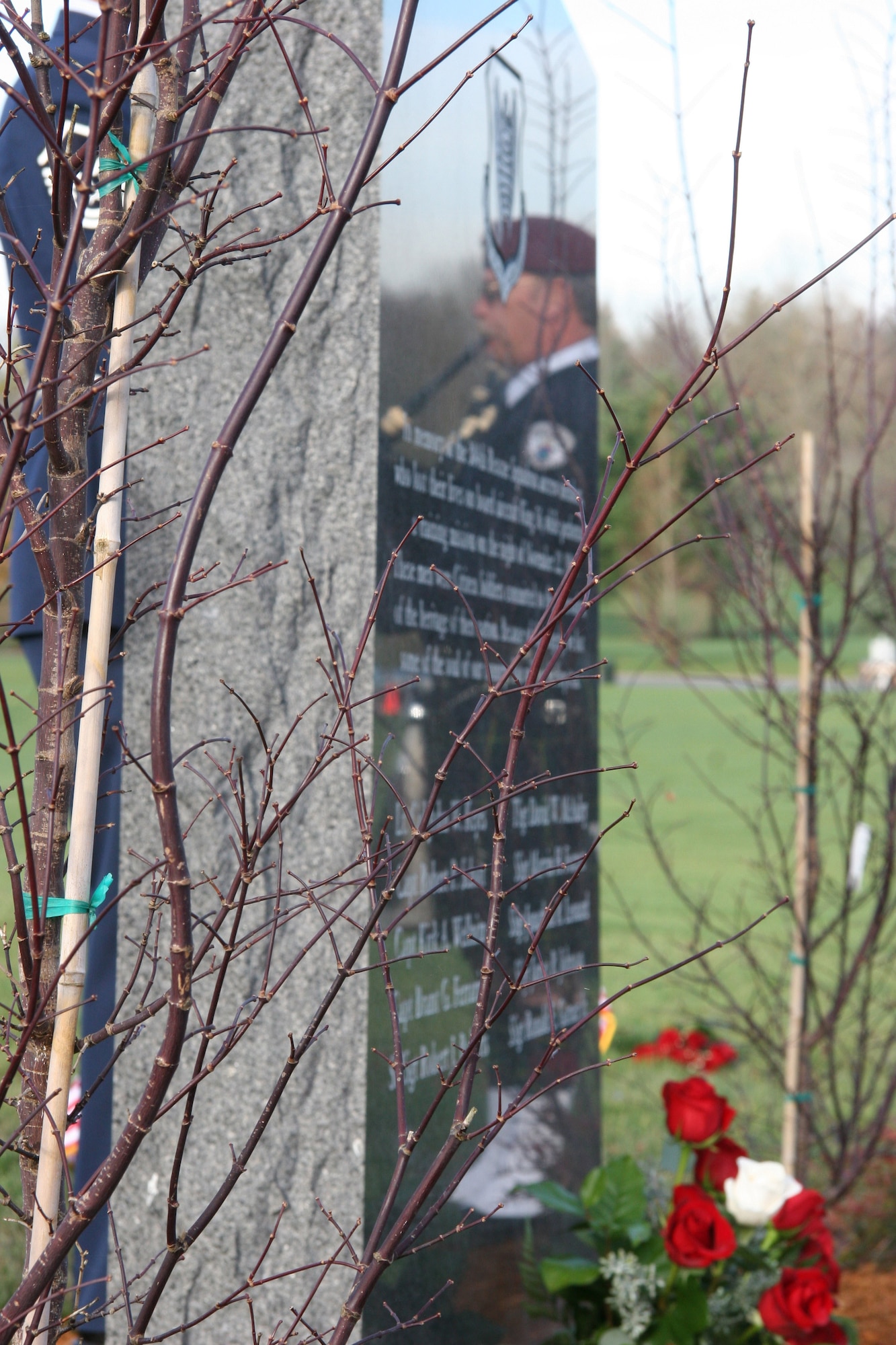 The memorial for the King 56 crew catches the reflection of Mr. John Pierson, bagpiper and former 304th Rescue Squadron pararescueman during a ceremony Nov. 17, 2006 at the Williamette National Cemetery.  (U.S. Air Force Photo/Master Sgt. Linda Welz)