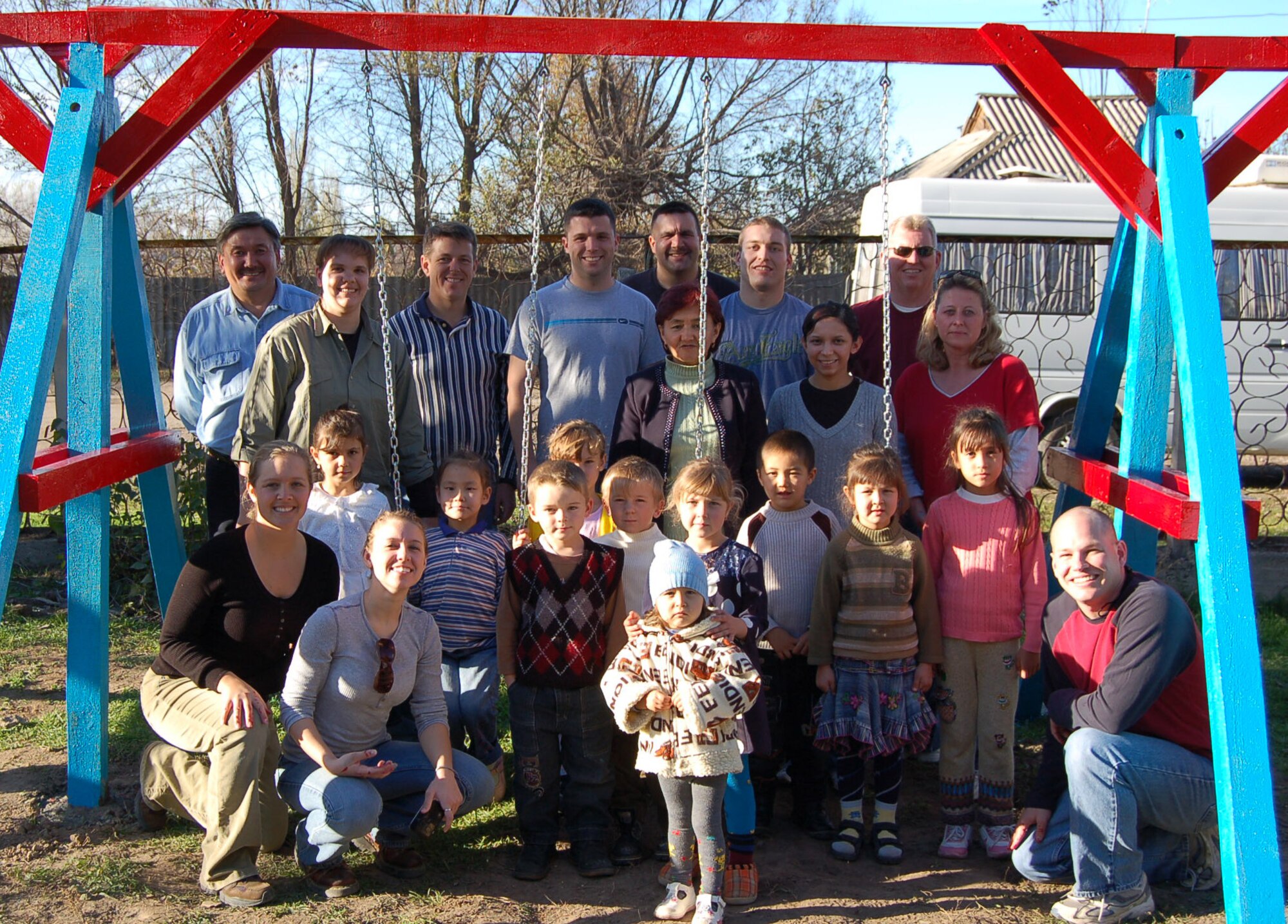 Airmen from Manas Air Base, Kyrgyzstan, pose for a picture with local kindergarteners after finishing work on a new swing set for the youngsters.  (U.S. Air Force Photo/Capt. Christy Stravolo)