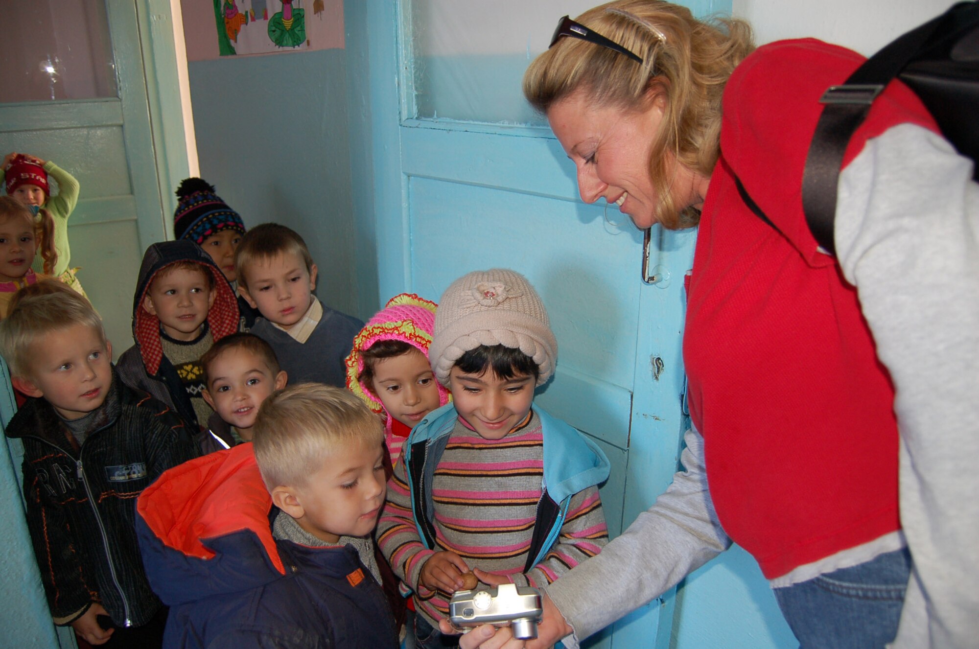 Master Sgt. Barbara Holley, 376th Air Expeditionary Wing administrator, shows some of the kindergarteners a picture she just took of them. Members of the 376th Air Expeditionary Wing and 376th Expeditionary Operations Group built and painted a swing set for the Solnyshko Kindergarten School near the village of Vinogradnoe, Kyrgyzstan, Nov. 16. “We are very thankful for the U.S. military and, God willing, this relationship will continue,” said Manzura Kushbaeva, the school's principal. Sergeant Holley is deployed from the 32nd Aerial Port Squadron, Pittsburgh, Pa. (U.S. Air Force Photo/Capt. Christy Stravolo)