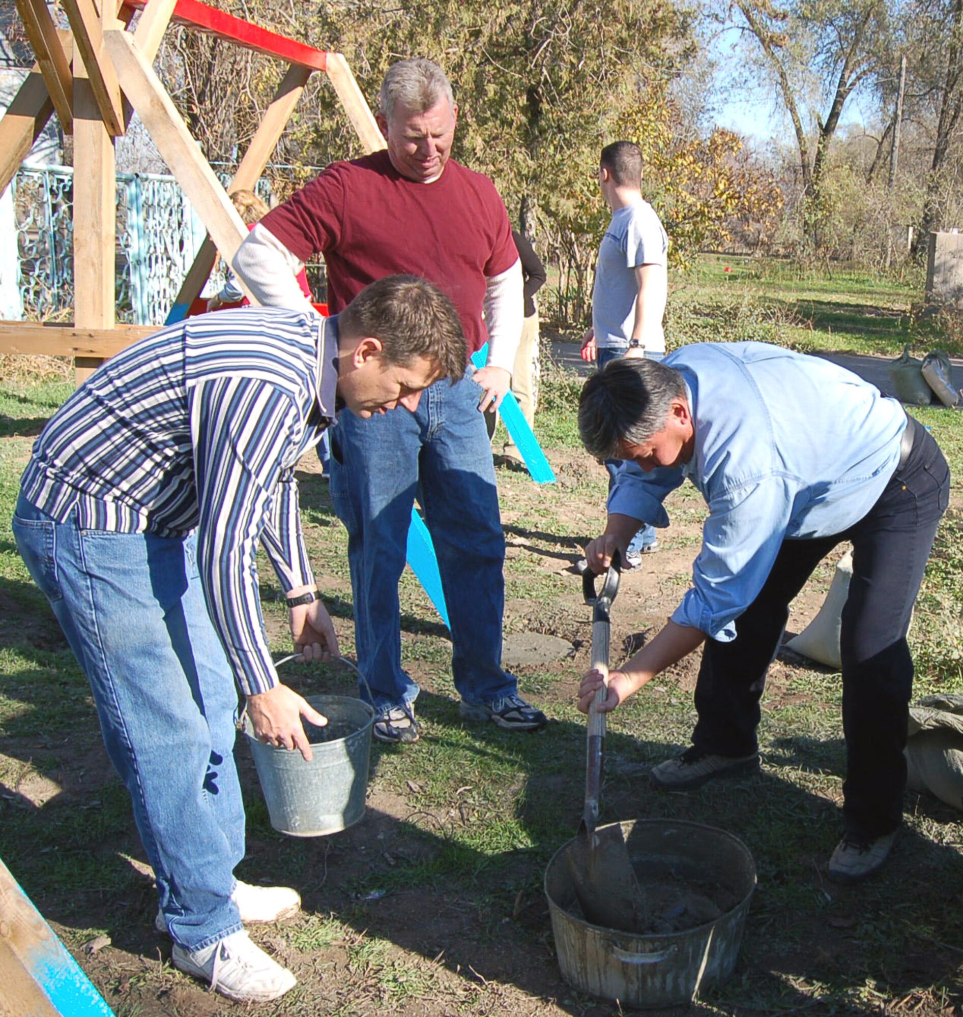 Volunteers from Manas Air Base, Kyrgyzstan, mix concrete to secure the posts of the swing set at the Solnyshko Kindergarten School near the village of Vidogradnoe Nov. 16.  (U.S. Air Force Photo/Capt. Christy Stravolo)
