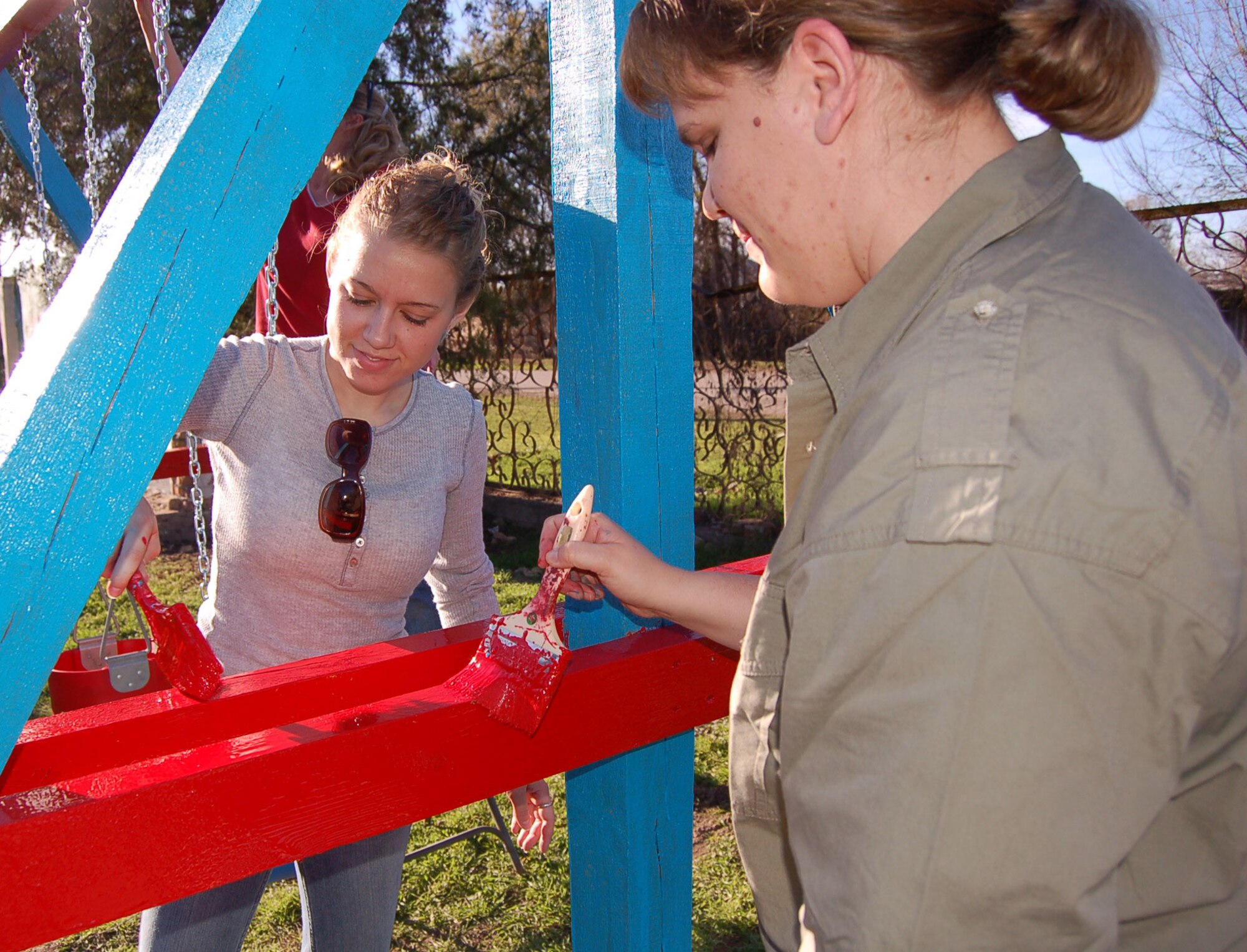 Senior Airman Cheri Baloun (left) and Staff Sgt. Melissa Wilhite, 376th Expeditionary Operations Support Squadron, put the finishing touches on a new swing set for kindergarteners in a nearby village. Airman Baloun, an intel analyst, is deployed from the 436 OSS at Dover AFB, Del., and Sergeant Wilhite, a weather forecaster, is deployed from the 319 OSS at Grand Forks AFB, N.D. (U.S. Air Force Photo/Capt. Christy Stravolo)