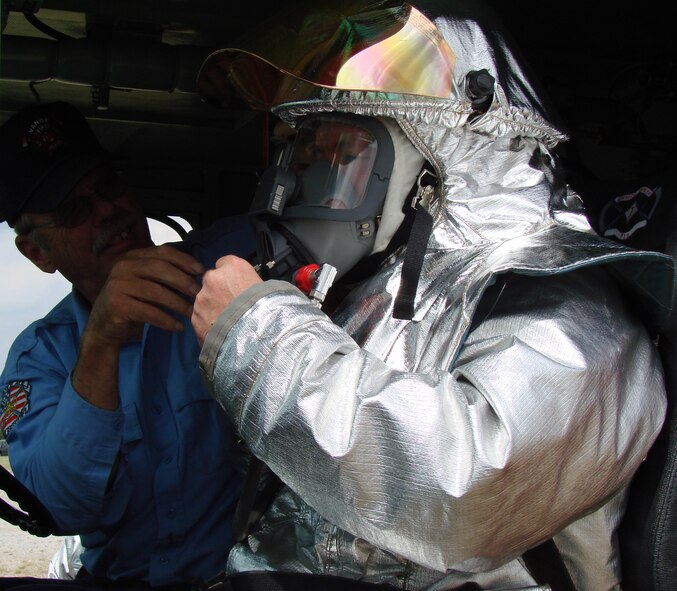 (Photo by Capt. Tony Wickman) John Wilkins, Vance Fire Department driver/operator, helps Col. Bryan Benson, 71st Flying Training Wing commander, secure his personal protective equipment before responding to a simulated aircraft fire at the Vance airfield rescue firefighting facility at the south end of the runway Aug. 22. Colonel Benson and Col. Christopher Thelen, 71st Mission Support Group commander, joined the fire department for hands-on training.