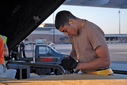 Airman 1st Class Ivan Frye, 437 APS aerial transportation specialist, connects chains to a pallet to be loaded onto the aircraft.  (Photo by Airman 1st Class Sam Hymas) (RELEASED)