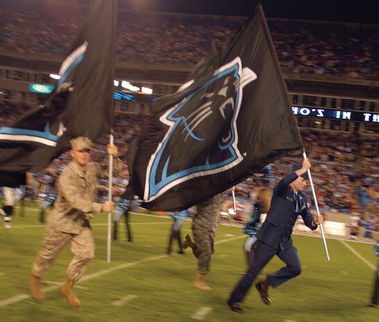 Staff Sgt. Steven Stone, 437th Civil Engineer Squadron explosive ordnance disposal technician, leads the Carolina Panthers onto the field before their Monday night game versus the Tampa Bay Buccaneers. Tech. Sgt. Curtis Jamison, 437th Communications Squadron, and Sergeant Stone, along with other members of the armed forces, were honored at the game for their role in fighting the Global War on Terrorism. (U.S. Air Force photo/Capt. Christopher Moore) (RELEASED)