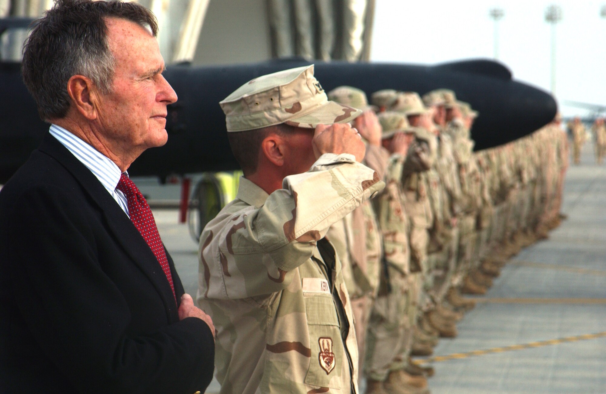 Former President George H.W. Bush listens to the national anthem with Airmen from the 380th Air Expeditionary Wing Nov. 20 in Southwest Asia. President Bush stopped by the wing to listen to a mission briefing and meet the Airmen assigned here. (U.S. Air Force photo/Master Sgt. Jason Tudor)