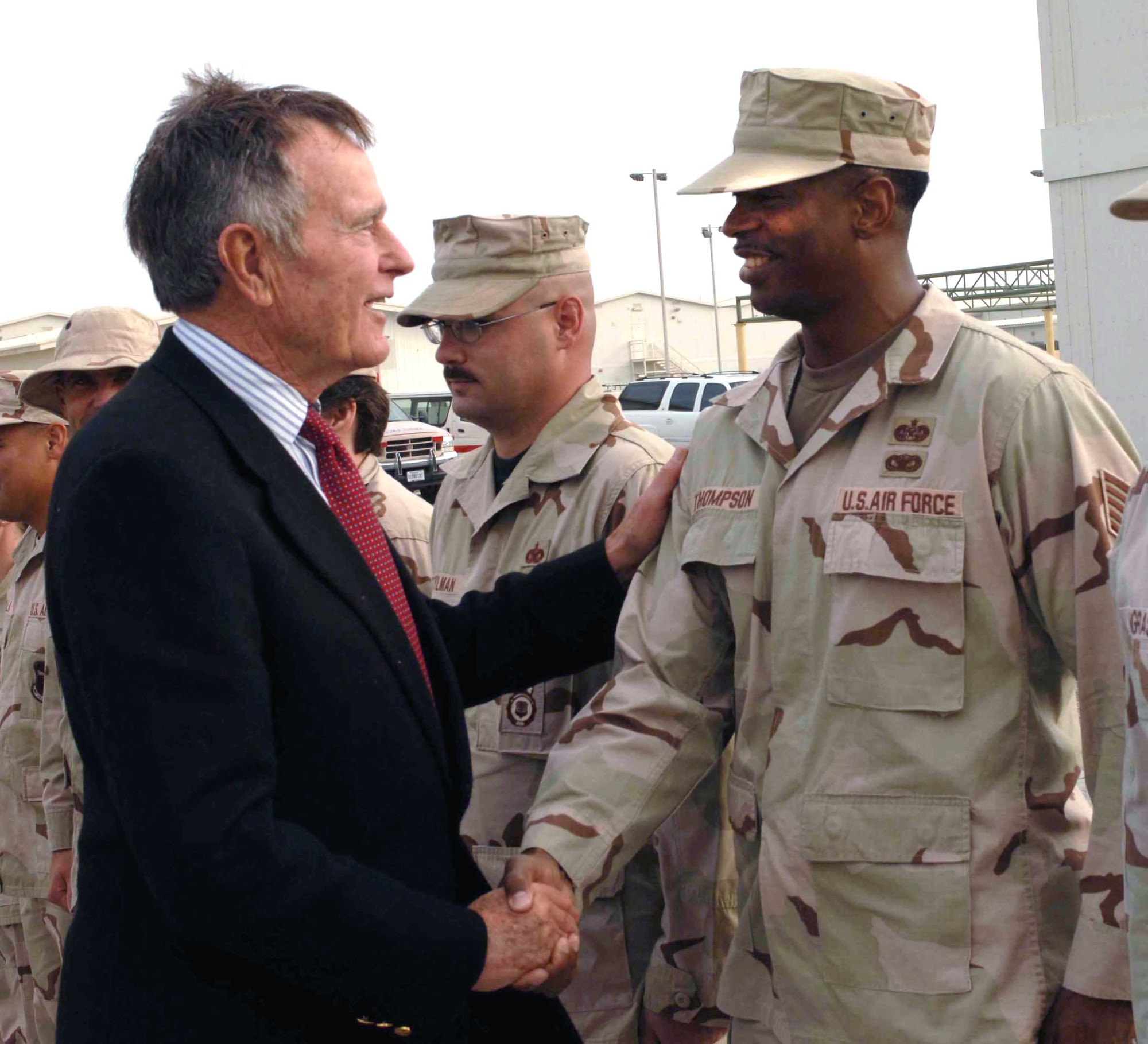 Former President of the United States George H.W. Bush shakes hands with Tech. Sgt. Ernest Thompson during a visit Nov. 20 to Southwest Asia. President Bush stopped by the 380th Air Expeditionary Wing to listen to a mission briefing and meet the Airmen assigned here. Sergeant Thompson a paralegal assigned to the 380th Air Expeditionary Wing. (U.S. Air Force photo/Tech. Sgt. Scott Seyer)
