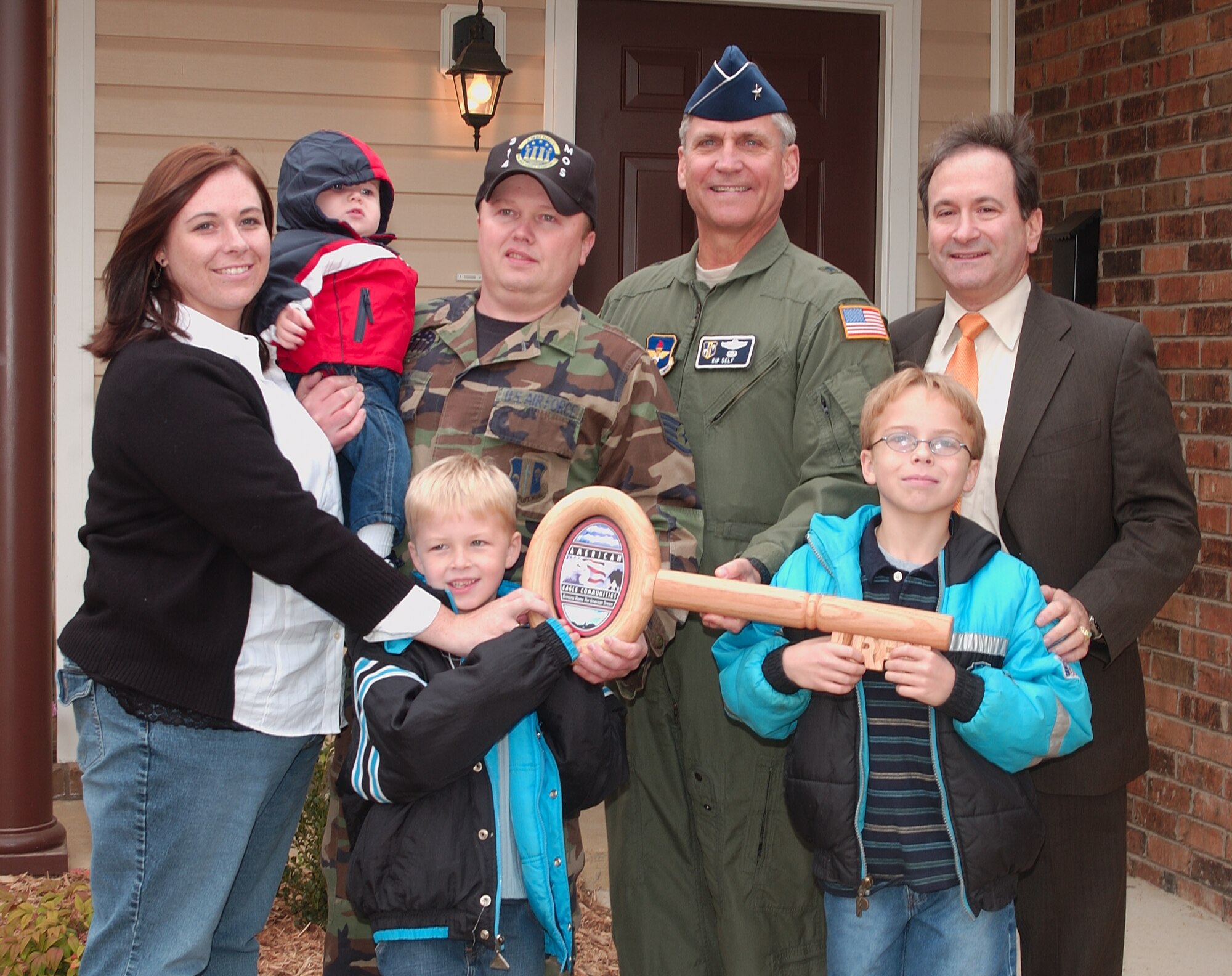 Brig. Gen. Kip Self, (right center) 314th Airlift Wing commander, and Howard Lazarus, (top right) American Eagle Communities director of operations, hand a ceremonial key to Staff Sgt. Mark Brown (left center) and his wife, Jennifer, and children, Dominic, 10, Christian, 7, and Carson, 1, during the base housing grand opening ceremony Nov. 1. The new houses are more spacious and have more amenities than previous base homes, residents say.