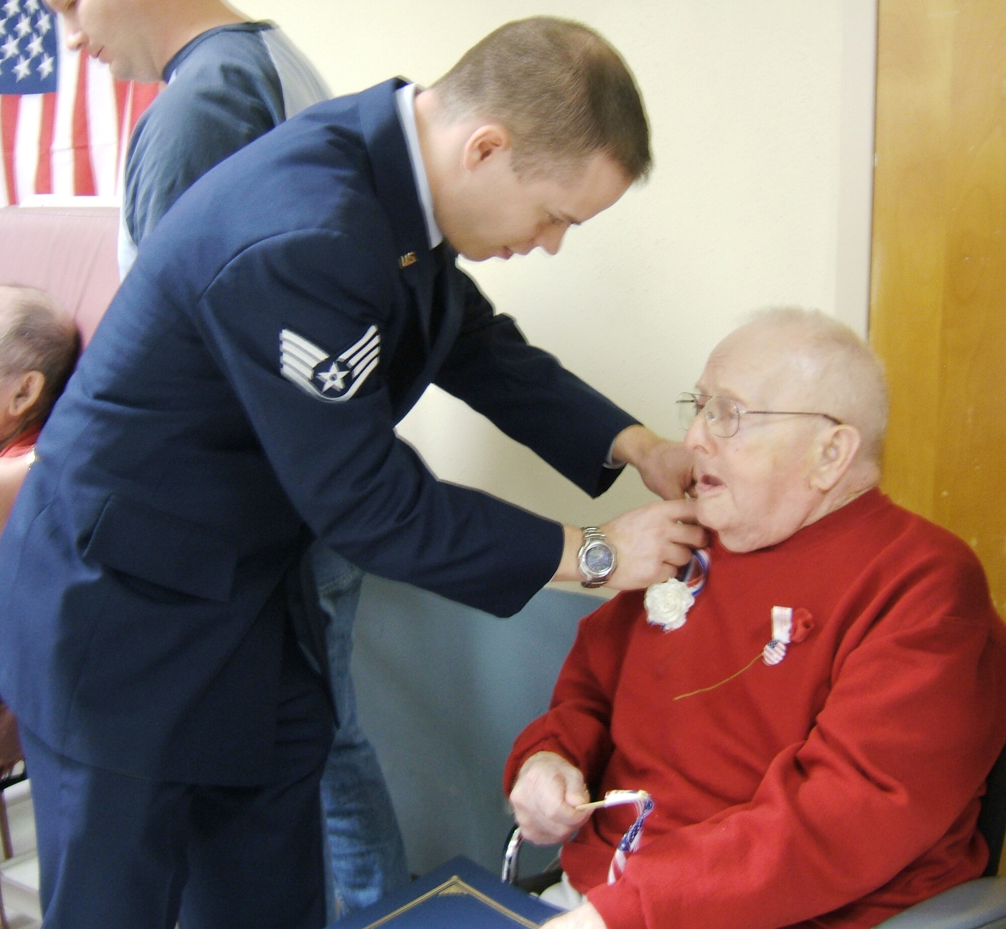 Staff Sgt. Chris Ammerman, 68th Electronic Warfare Squadron, places a pin on a veteran at the Crestview City Covenant Hospice.  More than 135 veterans were visited by wing members.