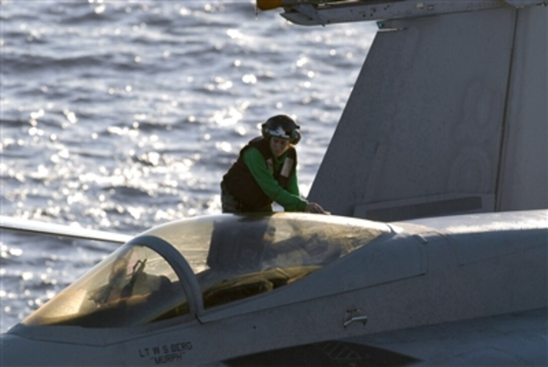 A squadron plane captain assigned to the "Fighting Redcocks" of Strike Fighter Squadron 22 wipes down the canopy of an F/A-18E Super Hornet on the flight deck of the USS Ronald Reagan in the Pacific Ocean, Nov. 16, 2006. 
