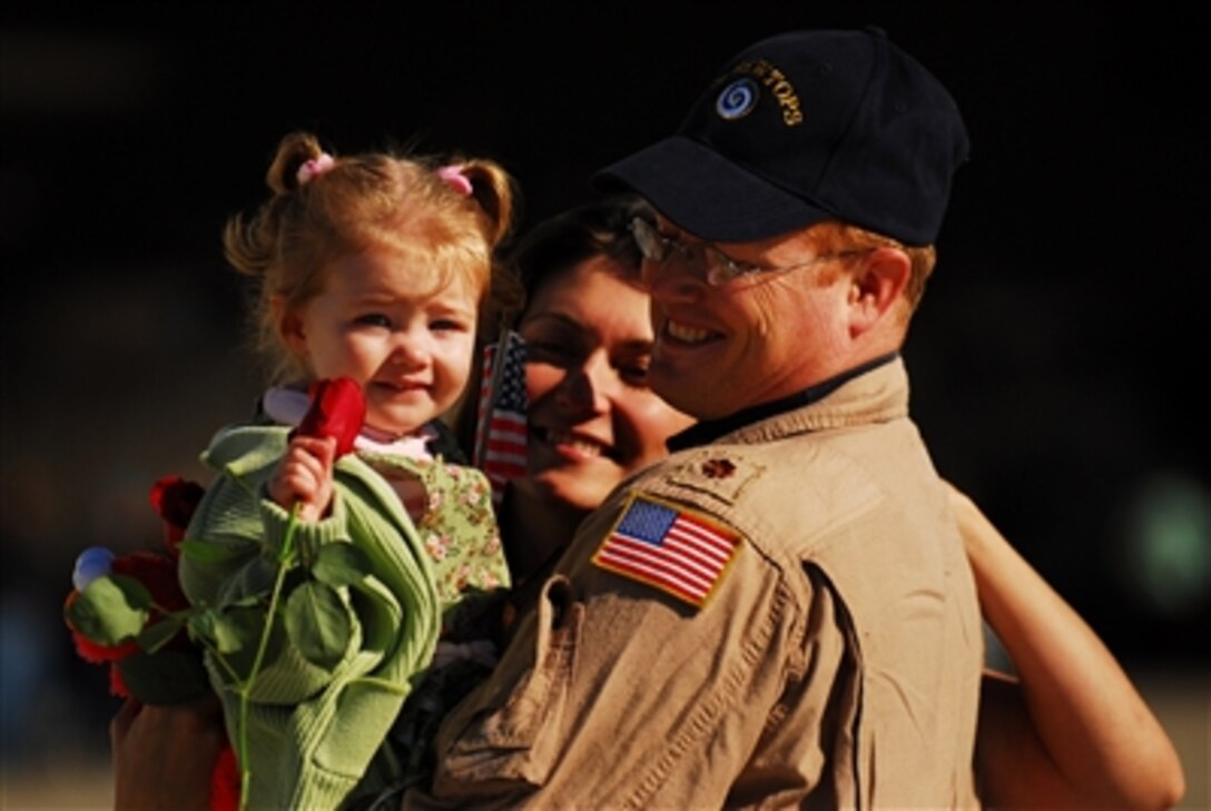 U.S. Navy Lt. Cmdr. Kevin Downey holds his daughter as his wife looks on after arriving at Chambers Field in Norfolk, Va., on Nov. 17, 2006, following a seven-month deployment aboard the USS Enterprise (CVN 65).  Downey is assigned to Carrier Airborne Early Warning Squadron 123.  