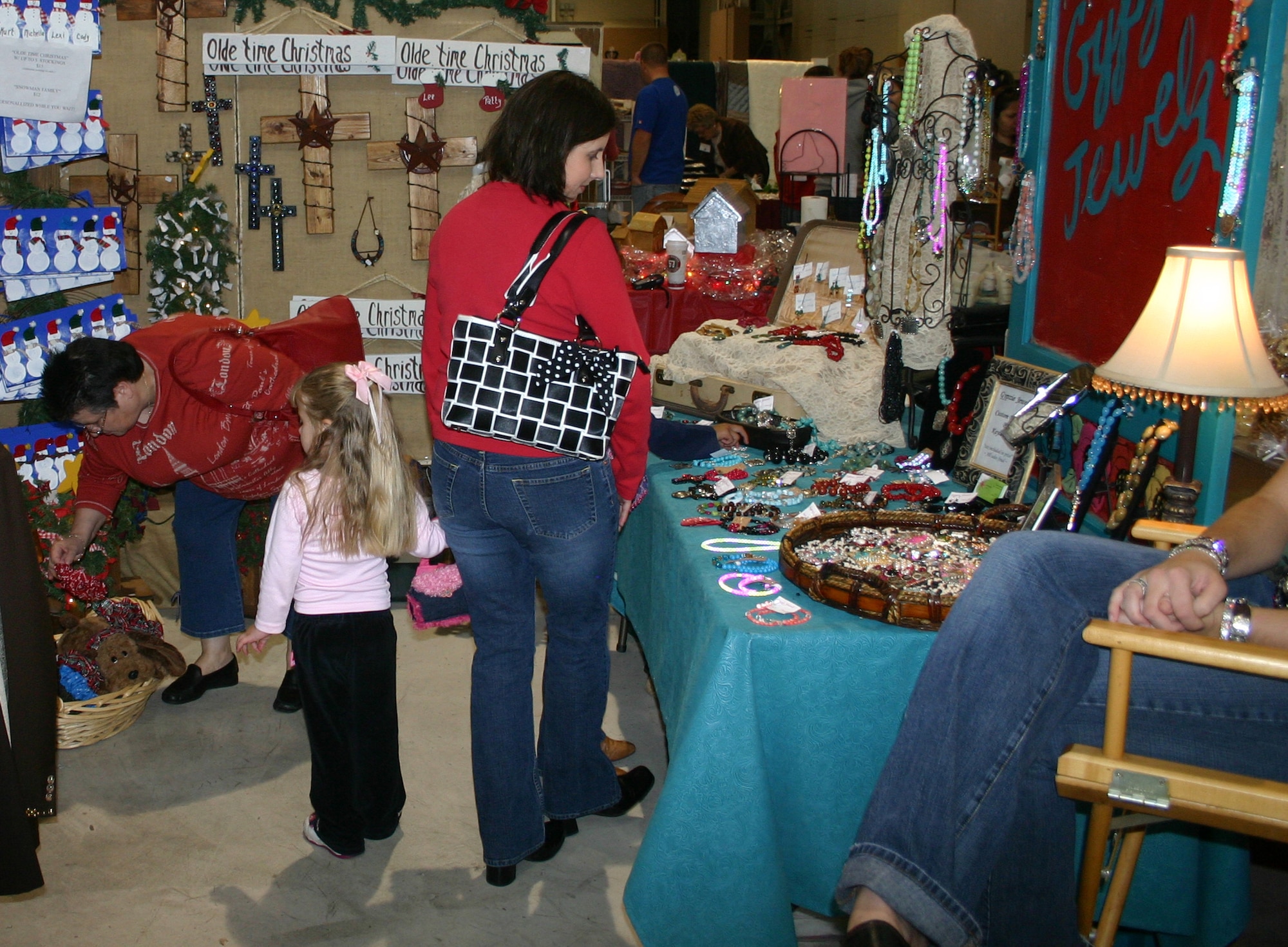 Larissa Parkey, right, a caregiver at the child development center, her daughter Ashton and mother Jackie Britt peruse a vendor’s display at the annual Hangar Holiday Sunday. (U.S. Air Force photo/Staff Sgt. Tonnette Thompson).