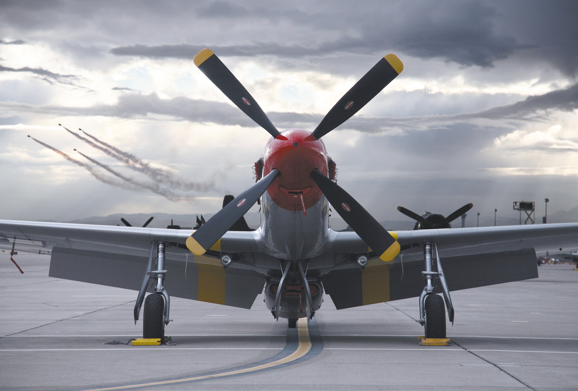 A vintage P-51 Mustang sits on the flightline while the U.S. Air Force Thunderbirds aerial demonstration team peforms during the Nellis Air Force Base, Nev., air show Nov. 11-12, 2006. More than 100,00 people attended the event. (U.S. Air Force photo/Lawrence Crespo)