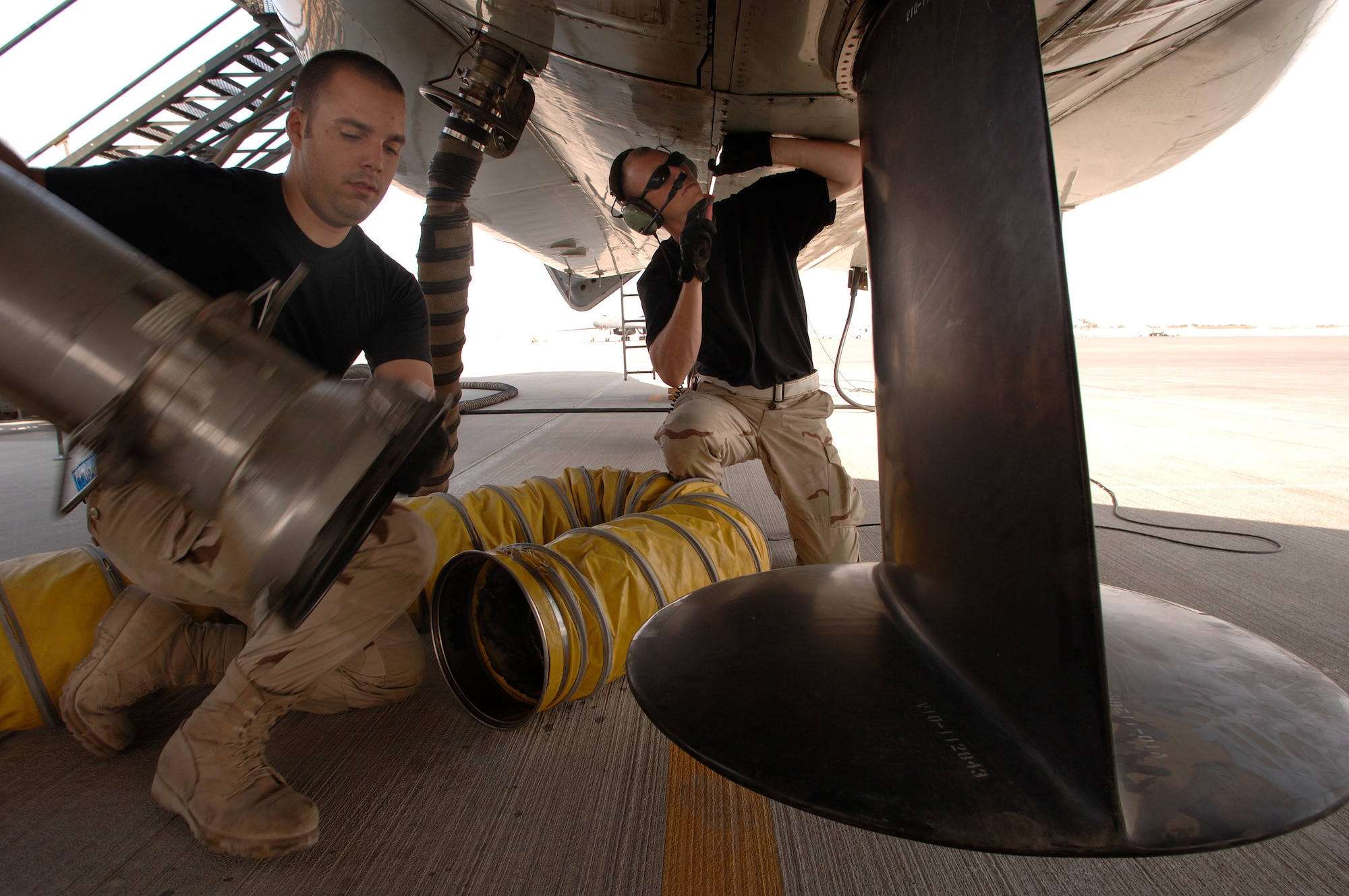 Senior Airman Matthew Campbell and Airman 1st Class Jonathan Campana remove one of many air conditioning hoses on an RC-135 Rivet Joint reconnaissance aircraft prior to its departure for a mission over southwest Asia. The hoses help maintain cool temperatures for the extensive inventory of electronics aboard the plane during its lengthy start up process. Both crew chiefs are deployed from the 55th Aircraft Maintenance Squadron from Offutt Air Force Base, Neb. (U.S. Air Force photo/Master Sgt. Scott Wagers)