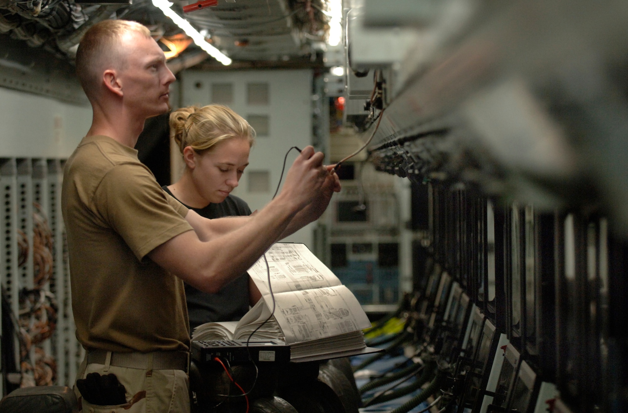 Senior Airman Dennis Kidwell and Airman 1st Class Ami Grabowski troubleshoot a bad radio frequency line aboard an RC-135 Rivet Joint at a forward-deployed location in Southwest Asia. Both are electronic warfare specialists. Airman Kidwell is deployed from the 488th Intelligence Squadron, Royal Air Force Mildenhall, England, and Airman Grabowski is from the 97th Intelligence Squadron from Offutt Air Force Base, Neb.  (U.S. Air Force photo/Master Sgt. Scott Wagers)