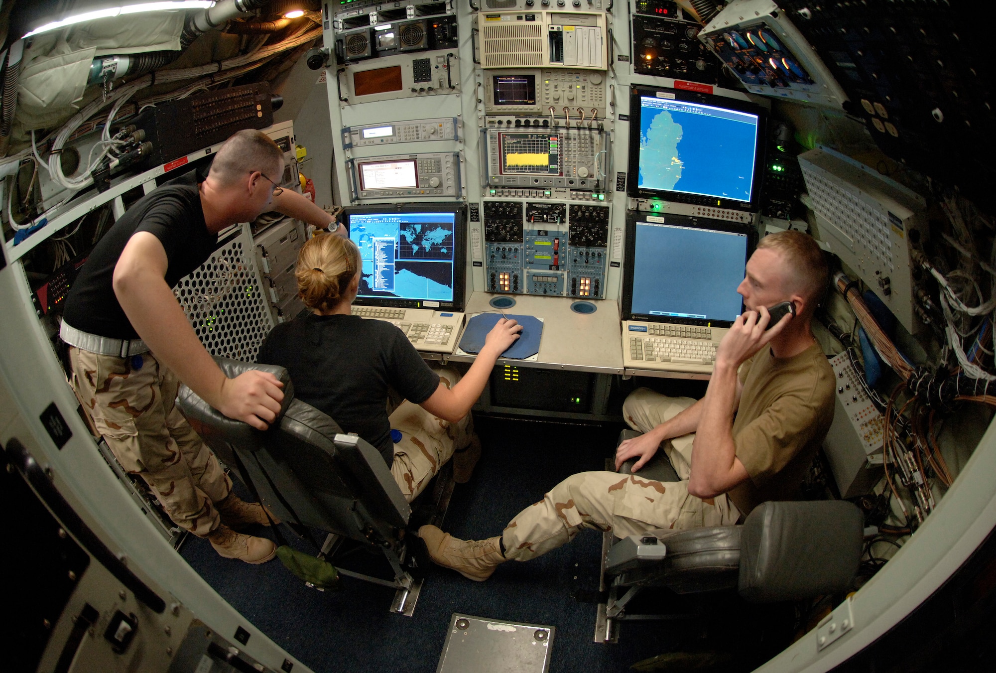 Senior Airman Weylin Oliver and Airman 1st Class Ami Grabowski create and route test signals from a maintenance station aboard an RC-135 Rivet Joint reconnaissance aircraft deployed to Southwest Asia while Senior Airman Dennis Kidwell fields a call from his maintenance supervisor. On average, it takes close to two years for these technicians to become 100 percent qualified to perform the 146 core tasks that are needed to maintain the planes sophisticated intelligence gathering hardware. The three are electronic warfare specialists. Airmen Grabowski and Oliver are from the 97th Intelligence Squadron from Offutt Air Force Base, Neb. Airman Kidwell is deployed from the 488th Intelligence Squadron, Royal Air Force Mildenhall, England. (U.S. Air Force photo/Master Sgt. Scott Wagers)