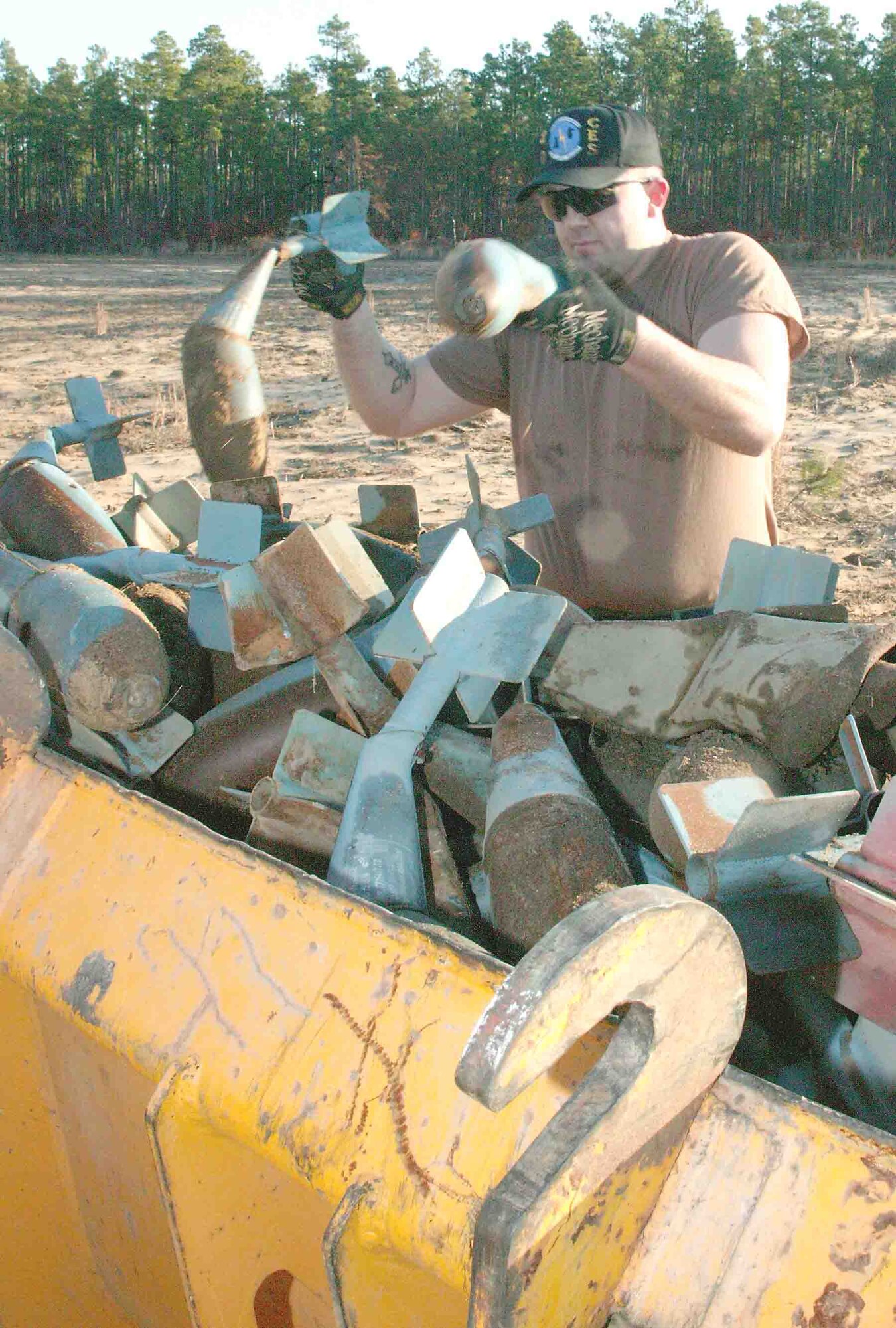 Senior Airman Eric Charlton, 20th Civil Engineer Squadron Explosive Ordnance Disposal technician, throws used, scrap bomb dummy units into the backhoe loader on Poinsett Electronic Combat Range. These BDUs will be recycled at a later time. (U.S. Air Force photo/Senior Airman John Gordinier)
