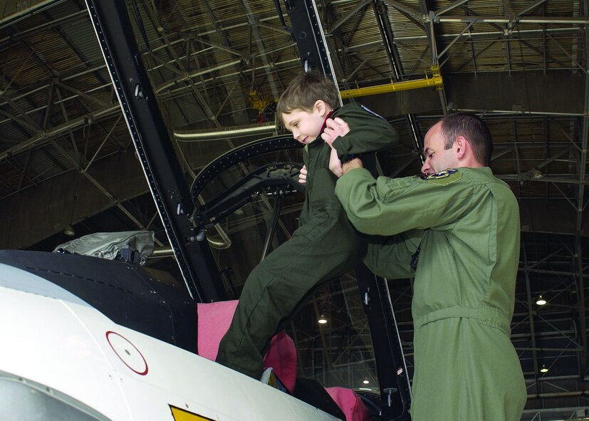 Maj. John Teichert, 411th Flight Test Squadron assistant operations officer, lifts Reilly Koyl, age 5, into an F-16 as part of the Pilot for a Day program. (Photo by Mark McCoy)