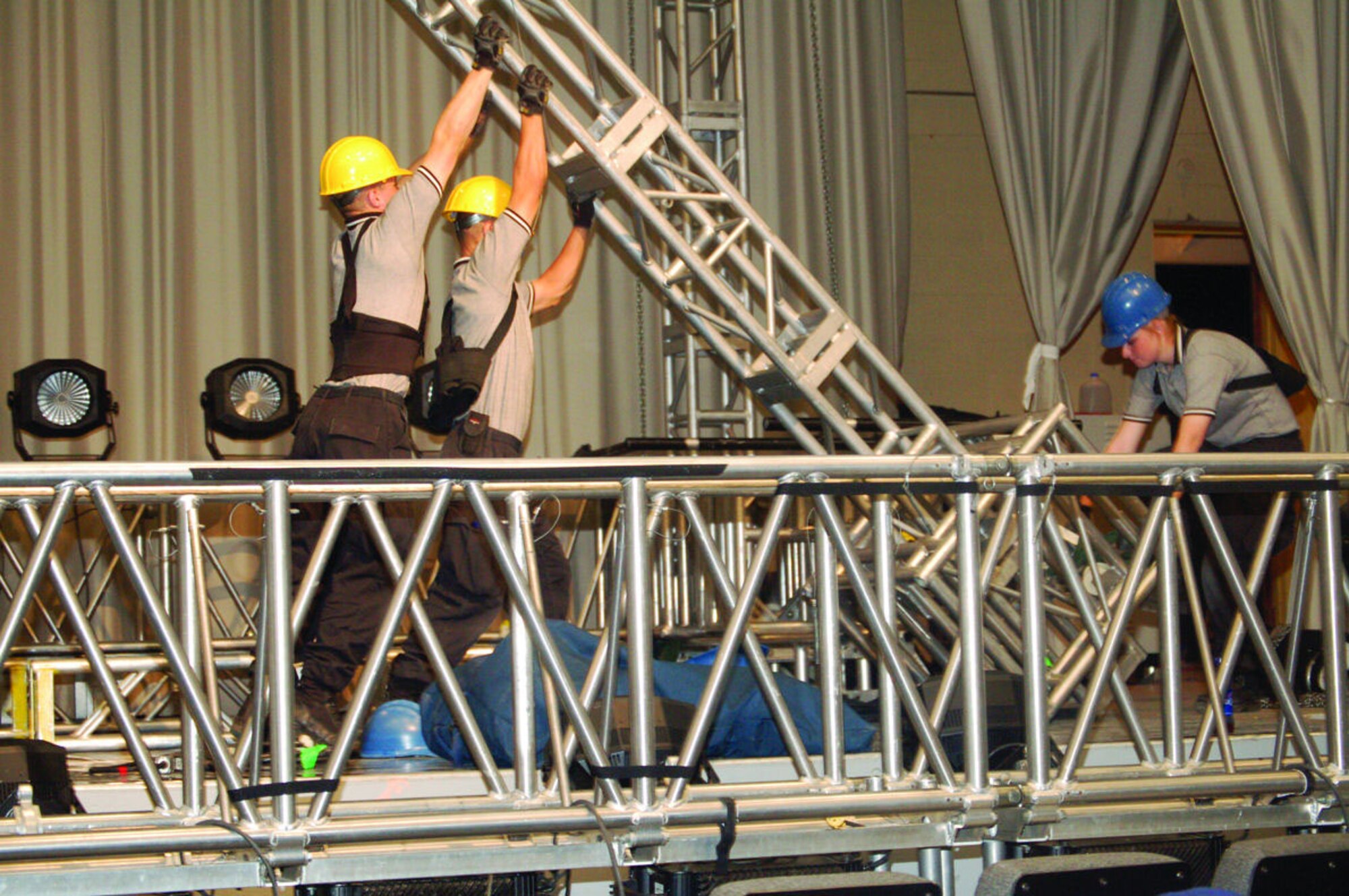 Three Tops in Blue staff members raise a truss for the lights and audio equipment. (Photo by Airman 1st Class Julius Delos Reyes)