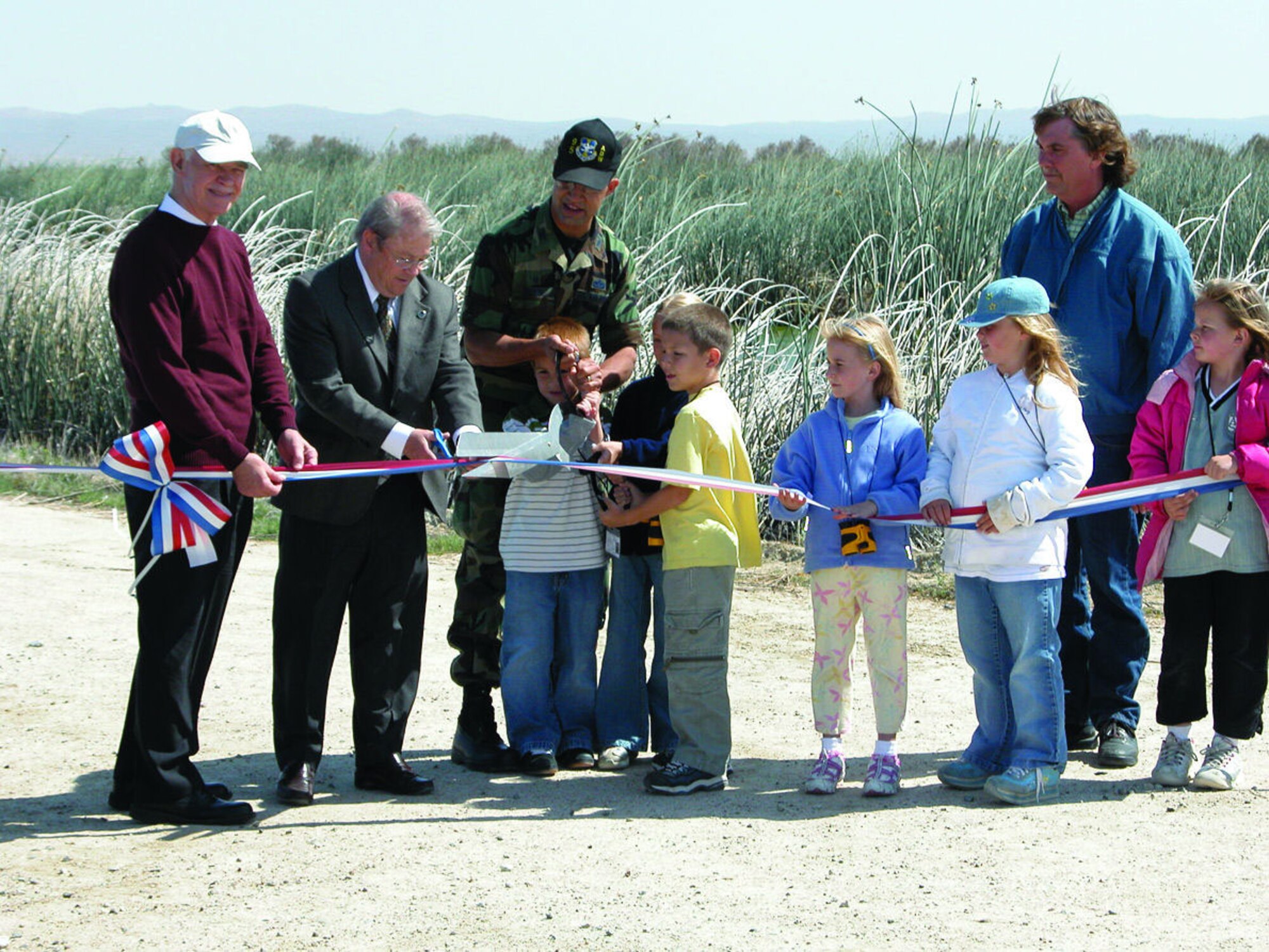 Col. Drew Jeter, 95th Air Base Wing commander, cuts the ribbon alongside second graders from Bailey Elementary School to officially open the updated Piute Ponds wetlands area here May 4, 2006. A new observation deck and several informational signs now line the walking path. (Photo by Miriam Horning)