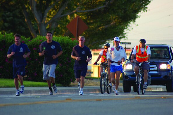 (From left to right) Edwards firefighters John Miller, Tyson Cardenas and Chris Lindsay run alongside former firefighter Ken Perry and two members from his medical team, bike riding, as Mr. Perry runs from the North Gate to the South Gate on June 2, 2006. Mr. Perry crossed Edwards as part of a 104.8-mile run benefiting the Wildland Firefighter Foundation, a non-profit organization that helps injured firefighters and the families of firefighters killed in the line of duty.  (Photo by Capt. Catie Hague)