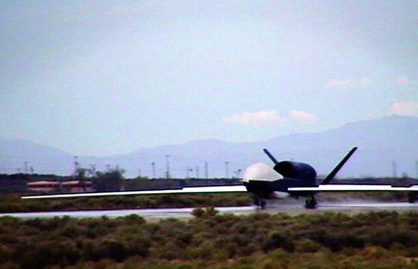 A Global Hawk Unmanned Aerial Vehicle raises a plume of water as it taxis on South Base during wet runway testing here recently.  (Photo by 2nd Lt. Benjamin Bennett)