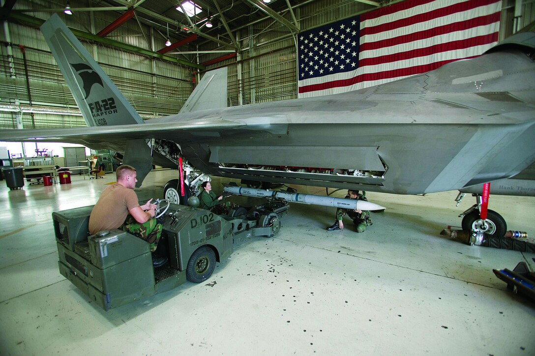 Senior Airman Daniel Myers, Staff Sgt. Daphne Jaehn and Staff Sgt. John Davenport load an AIM-120D Advanced Medium Range Air-to-Air Missile on an F-22A Raptor recently in preparation for noise and vibration testing here. The Airmen are all part of the 412th Aircraft Maintenance Squadron and are assigned to the F-22 Combined Test Force weapons flight.  (Photo by Kevin Robertson)