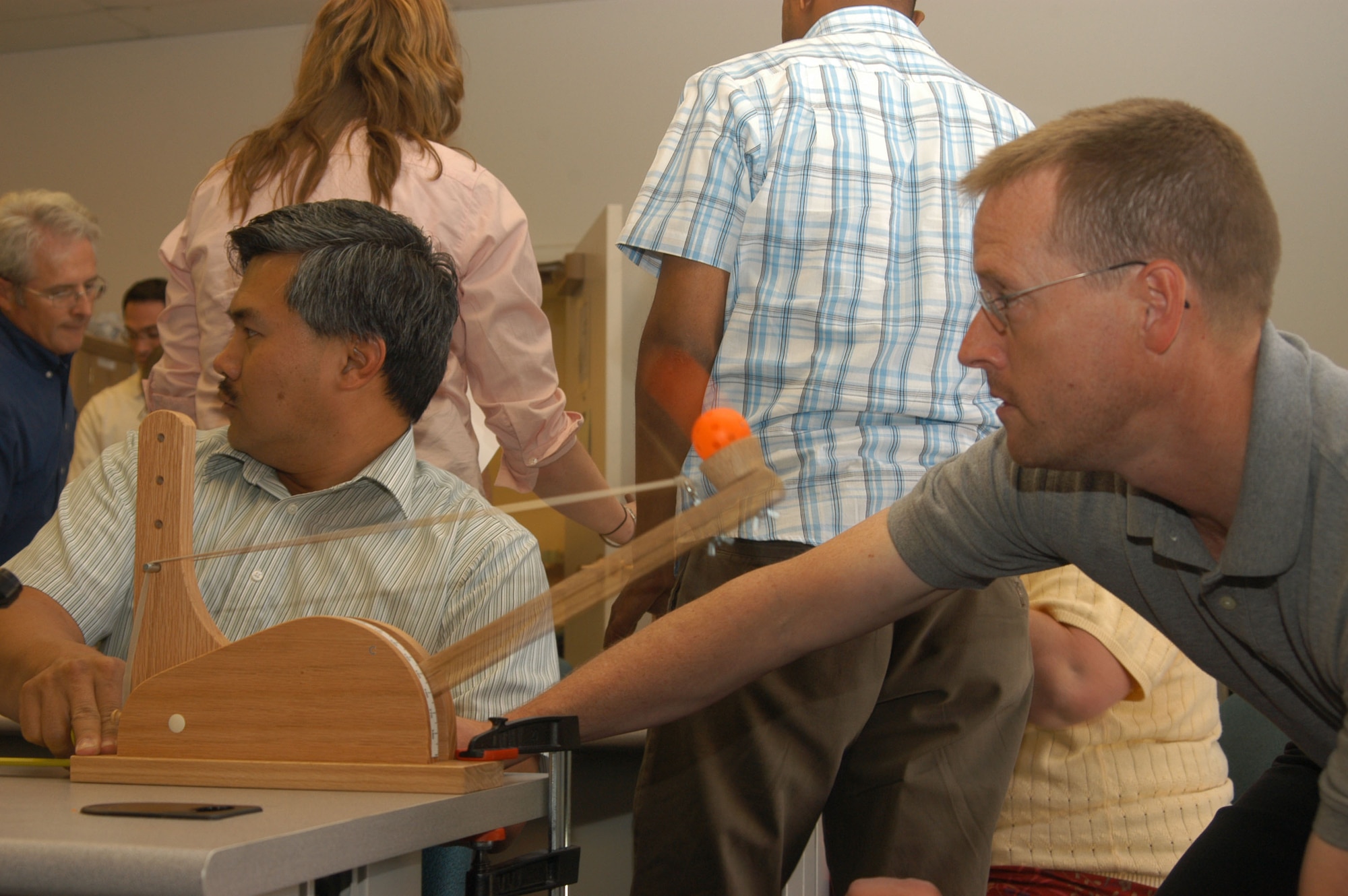 Pat Dubria, 418th Flight Test Squadron chief engineer, assists J.T. Stevens in launching foam balls from a "Statapult" — a tool which teaches students how to properly design tests and analyze the results.  (Photo by Airman Stacy Garcia)