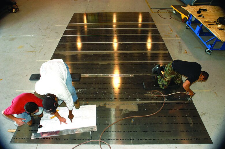 John Cracchiolo (left), Randy Morehead and Senior Airman Marlon Peeler, all structural maintenance craftsmen with the 412th Maintenance Squadron, assemble a ramp designed for C-5 landing gear tests scheduled for August 2006. The maintainers were tasked to build 16 ramps for low-speed taxi tests, and 20 for high-speed testing, and have used more than 200 sheets of aluminum, 300 sheets of plywood, 300 gallons of glue and thousands of fasteners putting the ramps together. (Photo by Christopher Ball)