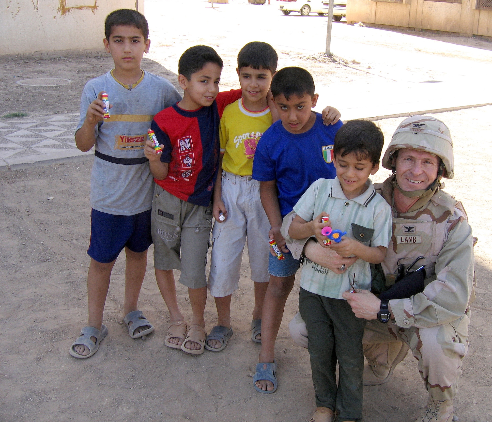 Colonel Duane Lamb, deployed to Balad Air Base, Iraq, from Maxwell Air Force Base, Ala., poses for a photo with children in Baghdad during a mission May 31, 2006. Colonel Lamb, who received his commission from the University of Alabama nearly 30 years ago, was presented the Bronze Star for his combat leadership during a ceremony Nov. 18, at his school's rival football game against Auburn University. (U.S. Air Force photo)