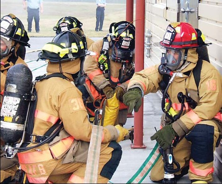Robins firefighters prepare to enter their structural live fire trainer. Before making entry, the firefighters must conduct buddy checks to make sure everyone is geared up correctly.