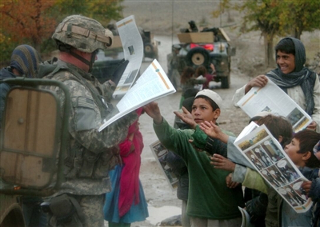 A U.S. Army soldier distributes newspapers to Afghan children during a patrol in Bagram, Afghanistan, Nov. 16, 2006. The soldier is assigned to the 102nd Infantry Regiment, Connecticut National Guard, attached to the 10th Mountain Division.