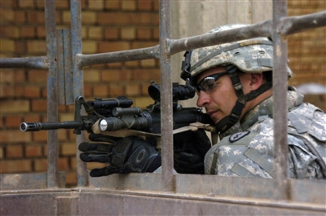 U.S. Army Spc. Bruce Blachly of Delta Company, 2nd Battalion, 27th Infantry Regiment uses the scope on his M 4 rifle to scan the distance during a joint U.S. and Iraqi cordon and search operation conducted in the Patika province of Iraq on Nov. 15, 2006. 