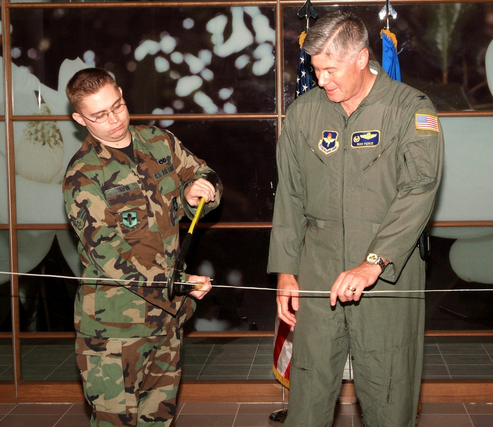 Senior Airman Joseph Turpin cuts a live phone cable Nov. 15 with the help of Col. Richard Pierce as part of the dedication ceremony demonstrating Keesler Medical Center's new Voice Over Internet Protocol phone system, which uses the Internet instead of phone lines to connect telephone signals. Colonel Pierce is vice commander of the 81st Training Wing at Keesler Air Force Base, Miss. Airman Turpin is assigned to the 81st Communications Squadron. (U.S. Air Force photo)