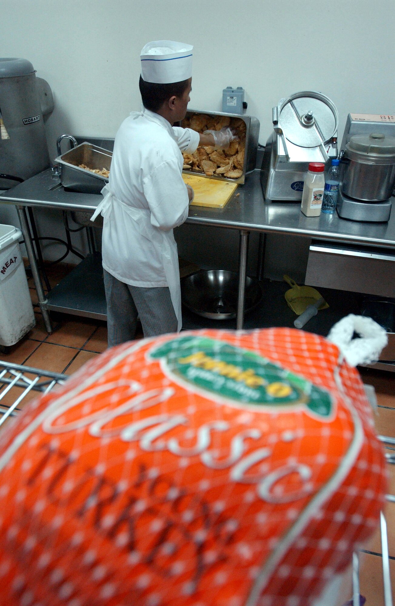 A contract food services worker prepares individual pieces of chicken for the dinner meal. Regular meals -- more than 11,000 of them -- continued while holiday meal preparation went on. (U.S. Air Force photo/Master Sgt. Jason Tudor)

