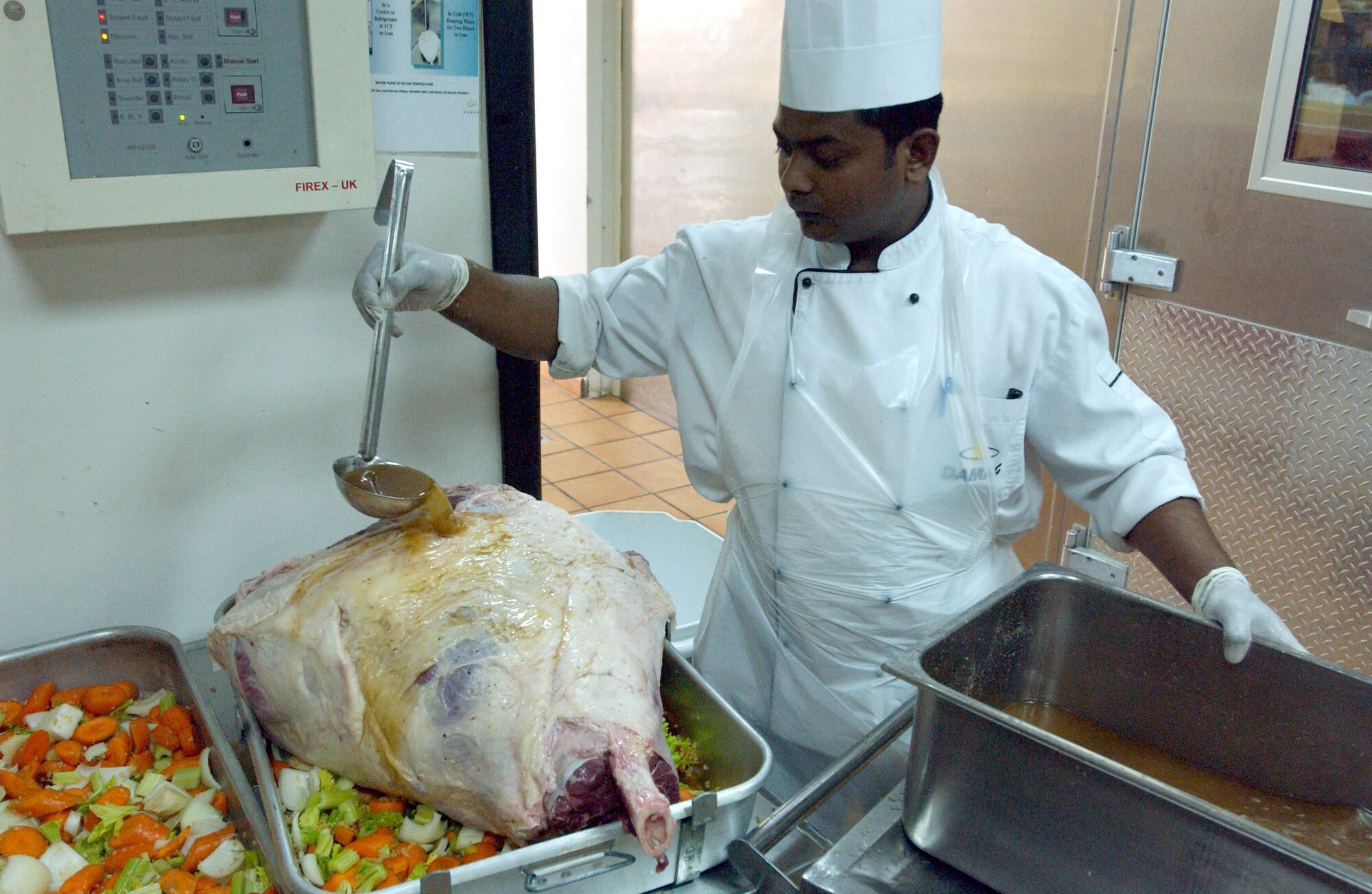 A contract food services worker bastes a 65-pound steamship round roast two days before Thanksgiving. Several of the roasts were prepared, along with about 1,700 pounds of turkey, for the 380th Air Expeditionary Wing's Thanksgiving meal. (U.S. Air Force photo/Master Sgt. Jason Tudor)
