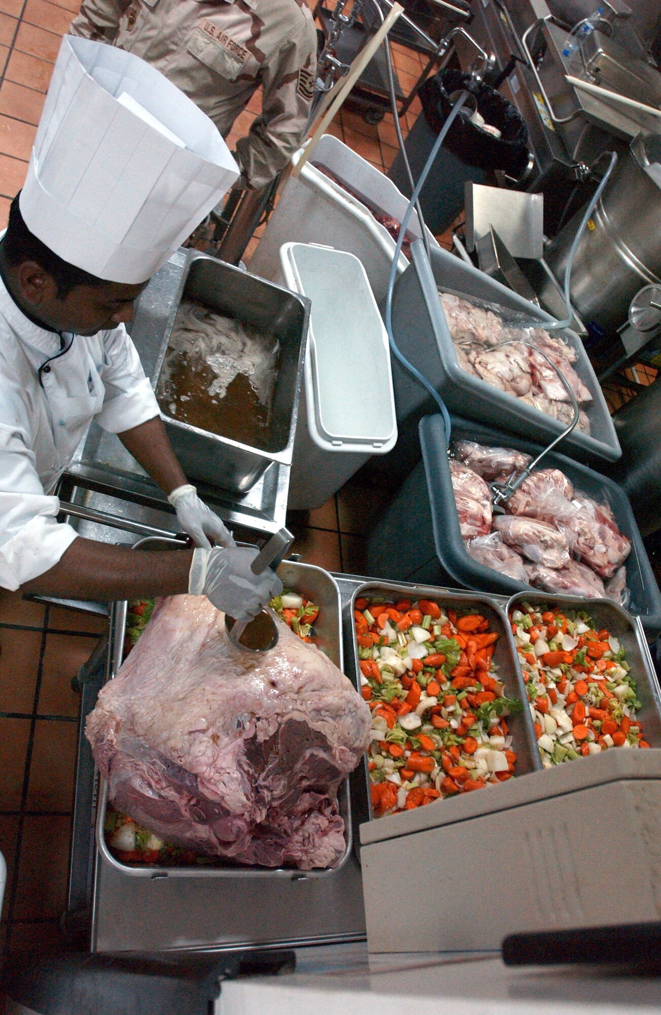 A contract food services worker bastes a 65-pound steamship round roast two days before Thanksgiving. Several of the roasts were prepared, along with about 1,700 pounds of turkey, for the 380th Air Expeditionary Wing's Thanksgiving meal. (U.S. Air Force photo/Master Sgt. Jason Tudor)

