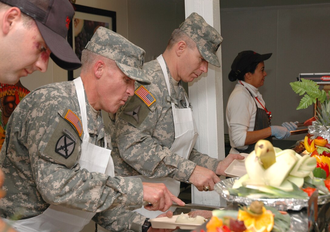 U.S. Army Command Sgt. Maj. Daniel R. Wood, left, senior enlisted advisor for Combined Forces Command Afghanistan, and Army Command Sgt. Maj. William J. Gainey, senior enlisted advisor to the chairman of the Joint Chiefs of Staff, serve Thanksgiving dinner to servicemembers on Bagram Air Base, Afghanistan. 
