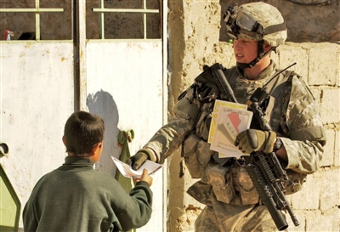 U.S. Army Cpl. Adam Swanson hands out flyers in the village of Ambulshabi, Iraq, Nov. 20, 2006. The flyers educate residents about reporting terrorist activities. Swanson is assigned to the 25th Infantry Division.