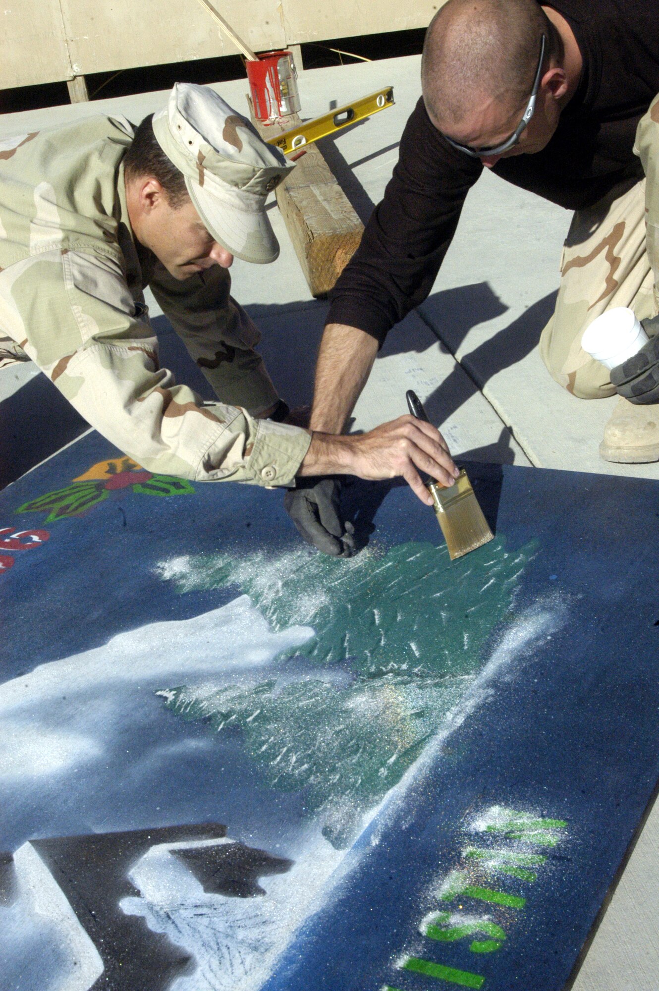 BAGRAM AIRFIELD, Afghanistan -- Major Bradley Waters, 455th Expeditionary Civil Engineer Squadron commander, and Senior Airman Stephen Johnson, 455 CES craftsmen, put final touches on a holidays greetings sign the squadron designed. More than 2,500 Airmen are deployed to Afghanistan in support of Operation Enduring Freedom this holiday season. (Air Force photo/Capt Vince King Jr.)