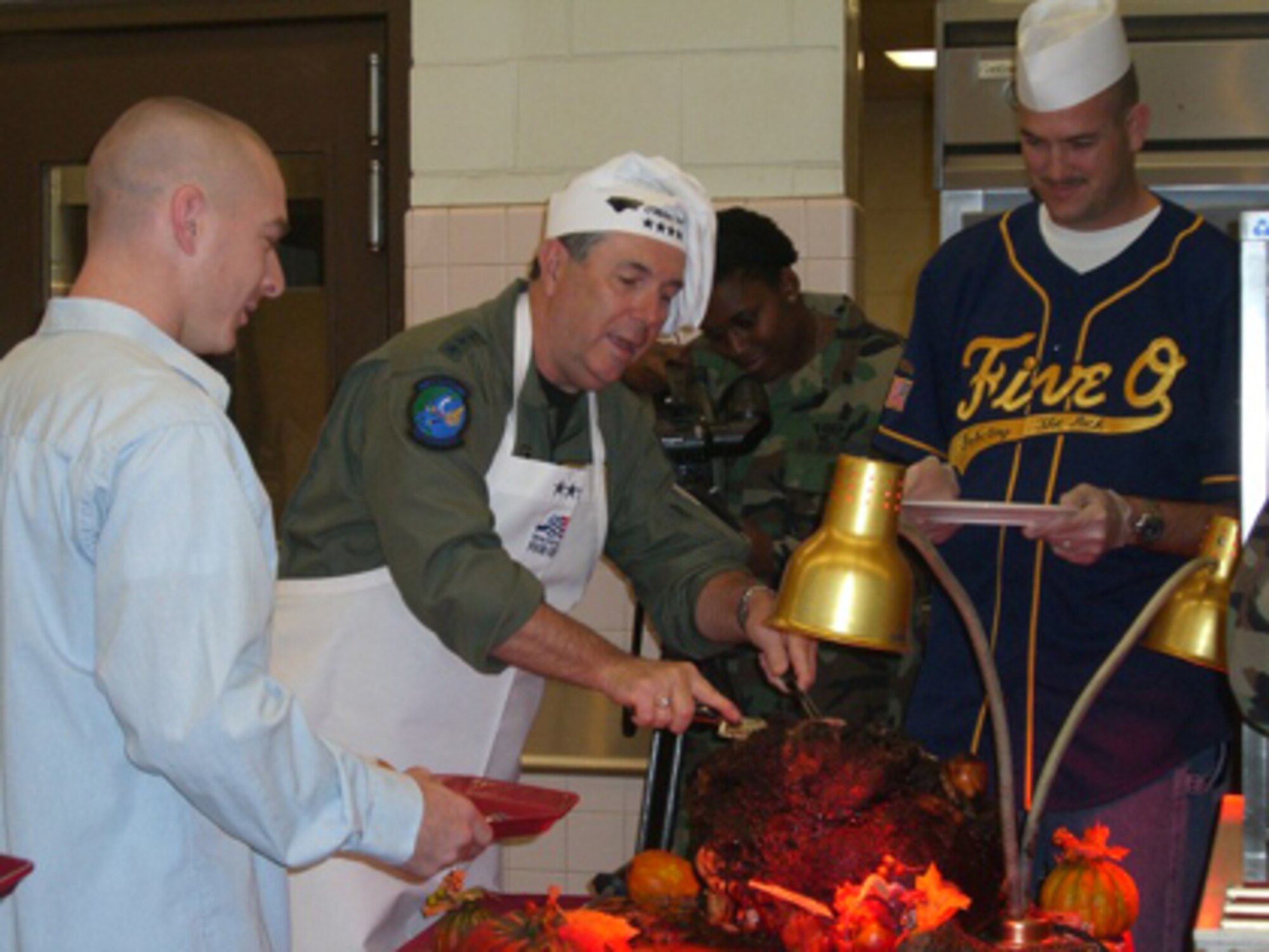 KUNSAN AIR BASE, Republic of Korea -- Gen. Paul V. Hester, Pacific Air Forces commander, carves and serves turkey to Airmen on Thanksgiving Day at the O’Malley Dining Facility.  