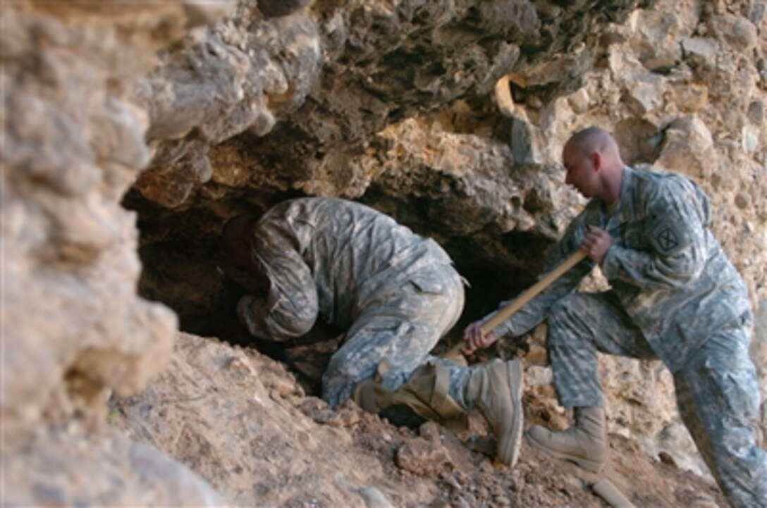 Command Sgt. Maj. Eugene Spencer (left) and Sgt. Michael Schobey enlarge the opening of a cave during a search for weapons caches near Landikheyl, Afghanistan, on Nov. 25, 2006.  The soldiers are from the 10th Mountain Division (Light Infantry).  