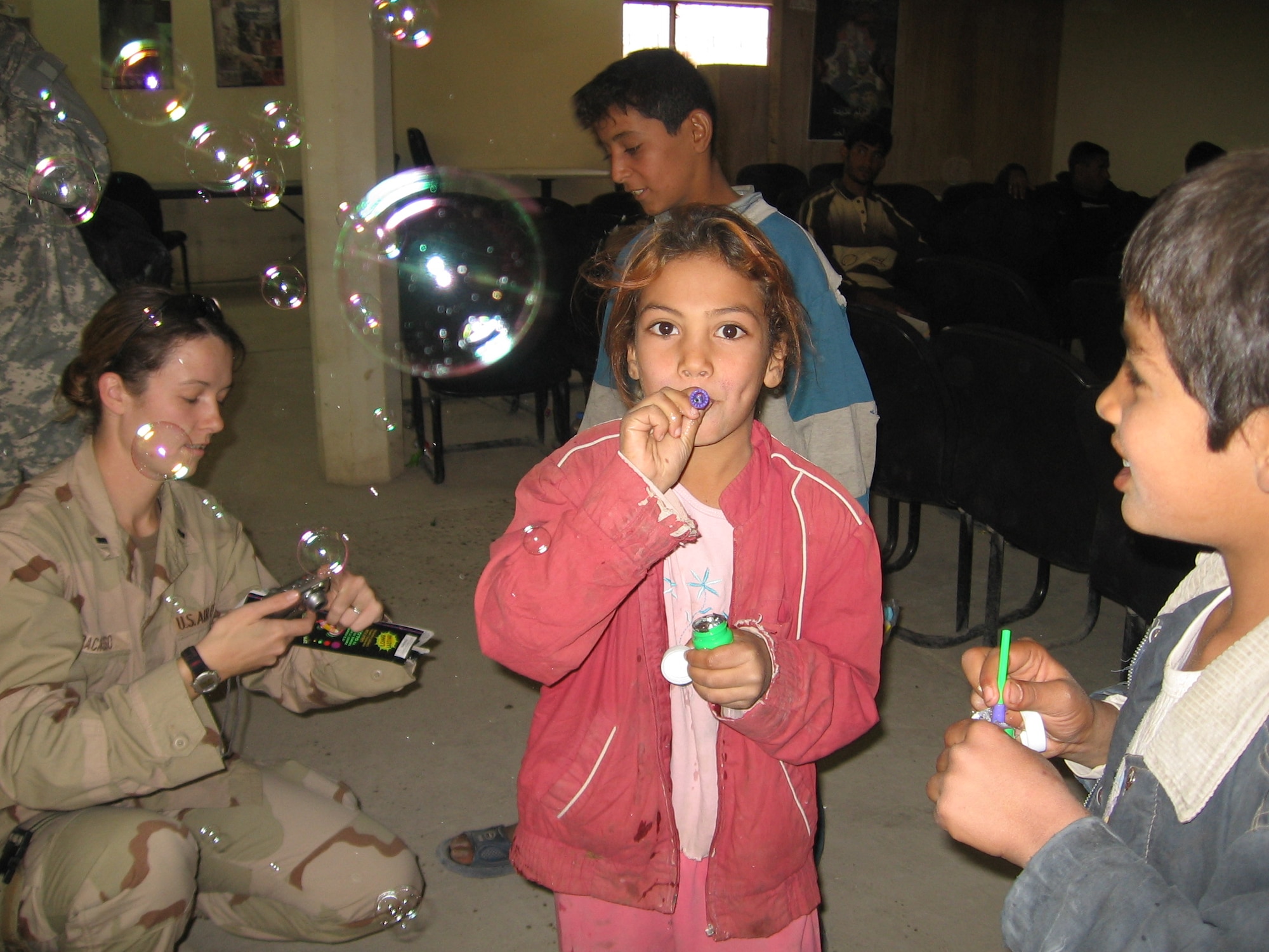 Children gather around to get toys and candy from 1st Lt. Lea Ann Fracasso during her visit to a Civil Military Operations Center in Baghdad. Lieutenant Fracasso currently is deployed from Wright-Patterson Air Force Base, Ohio, to Camp Victory, Iraq. (Photo by Capt. J. Elaine Hunnicutt)

