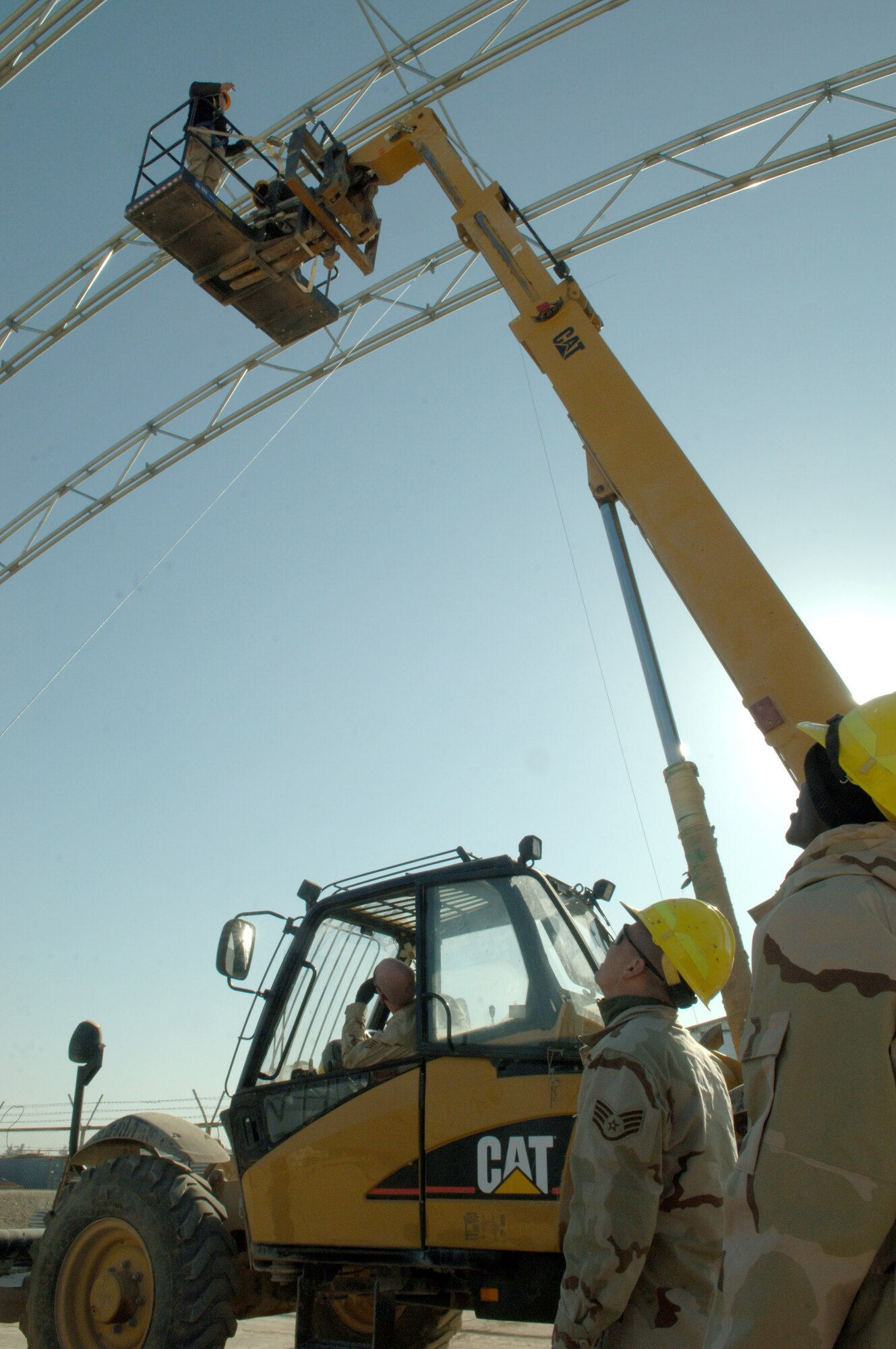 Airmen from the 332nd Expeditionary Civil Engineer Squadron Structures look on as Senior Airman Brandon Braley gives directions to the crew on the ground Nov. 26 at the new Hunter Unmanned Aerial Vehicle shelter. The 20-day project at Balad Air Base, Iraq., will take approximately 3,200 man hours to complete. (U.S. Air Force photo/Airman 1st Class Chad M. Kellum)
