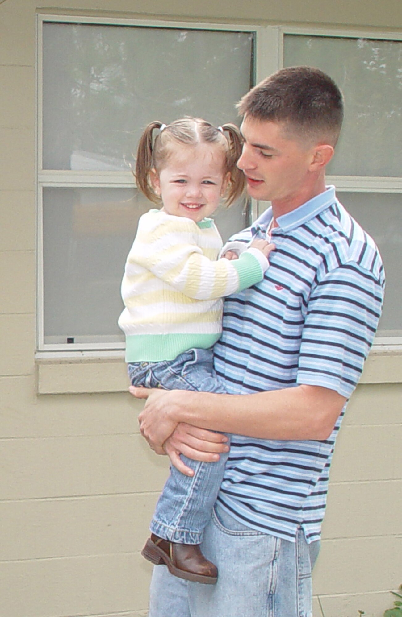 Airman Goldman holds his 2-year-old daughter Emilie in front of his house on Eglin AFB.  (Photo by Capt. Saje Park)