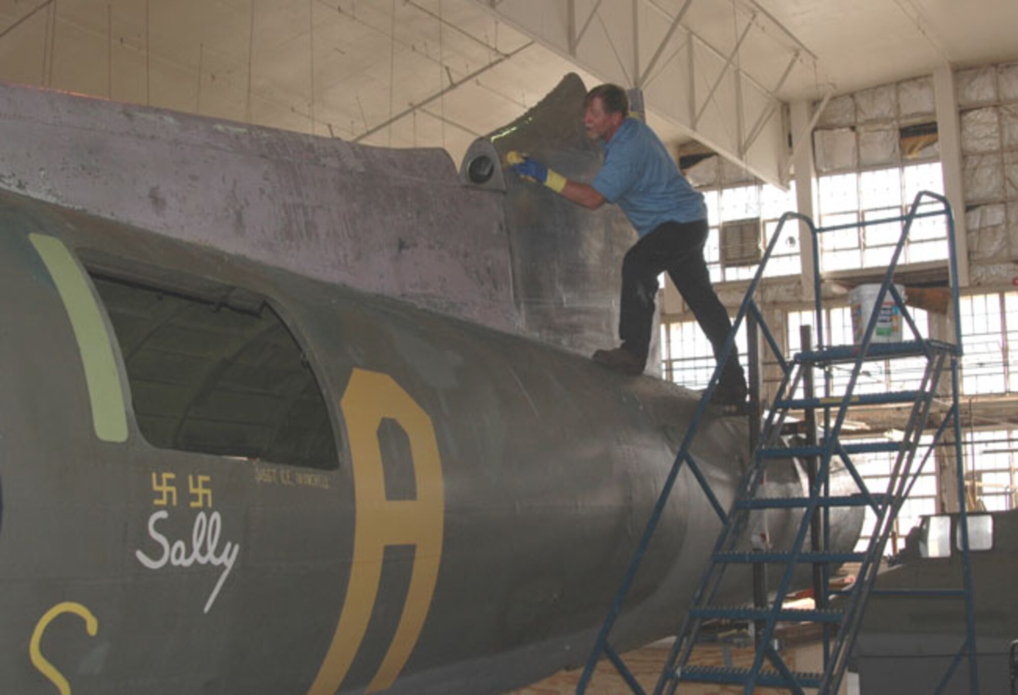 Mr. Bob Webb, restoration technician, wipes down the Memphis Belle after an application of AeroChem&rsquo;s Dekote paint stripper. 