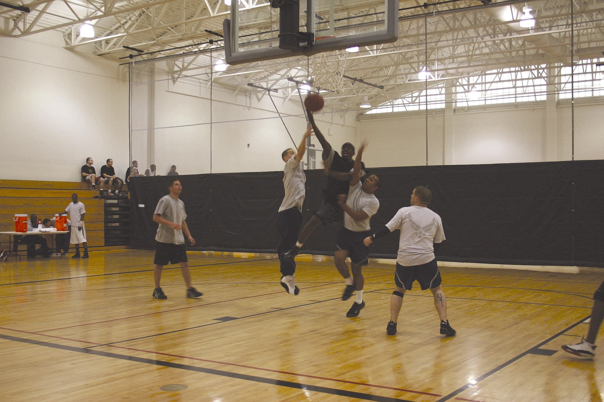 Team McGuire Airmen compete in the 3-on-3 basketball tournament Wednesday as part of the Team McGuire Sports Day events. The day’s activities began with a warrior run in the morning and included volleyball, flag football, golf and a bench press competition. The day concluded with a volleyball competition between the Chiefs/Shirts and the Eagles. The fitness center and health and wellness center staff are encouraging Team McGuire members to keep active during the holiday season to combat the weight gain often associated with holiday meals and baking. See the article on how to get involved with the 12 Days of Fitness at http://public.mcguire.amc.af.mil/news/story.asp?id=123033423. (U.S. Air Force Photo by Senior Airman Danielle Johnson)