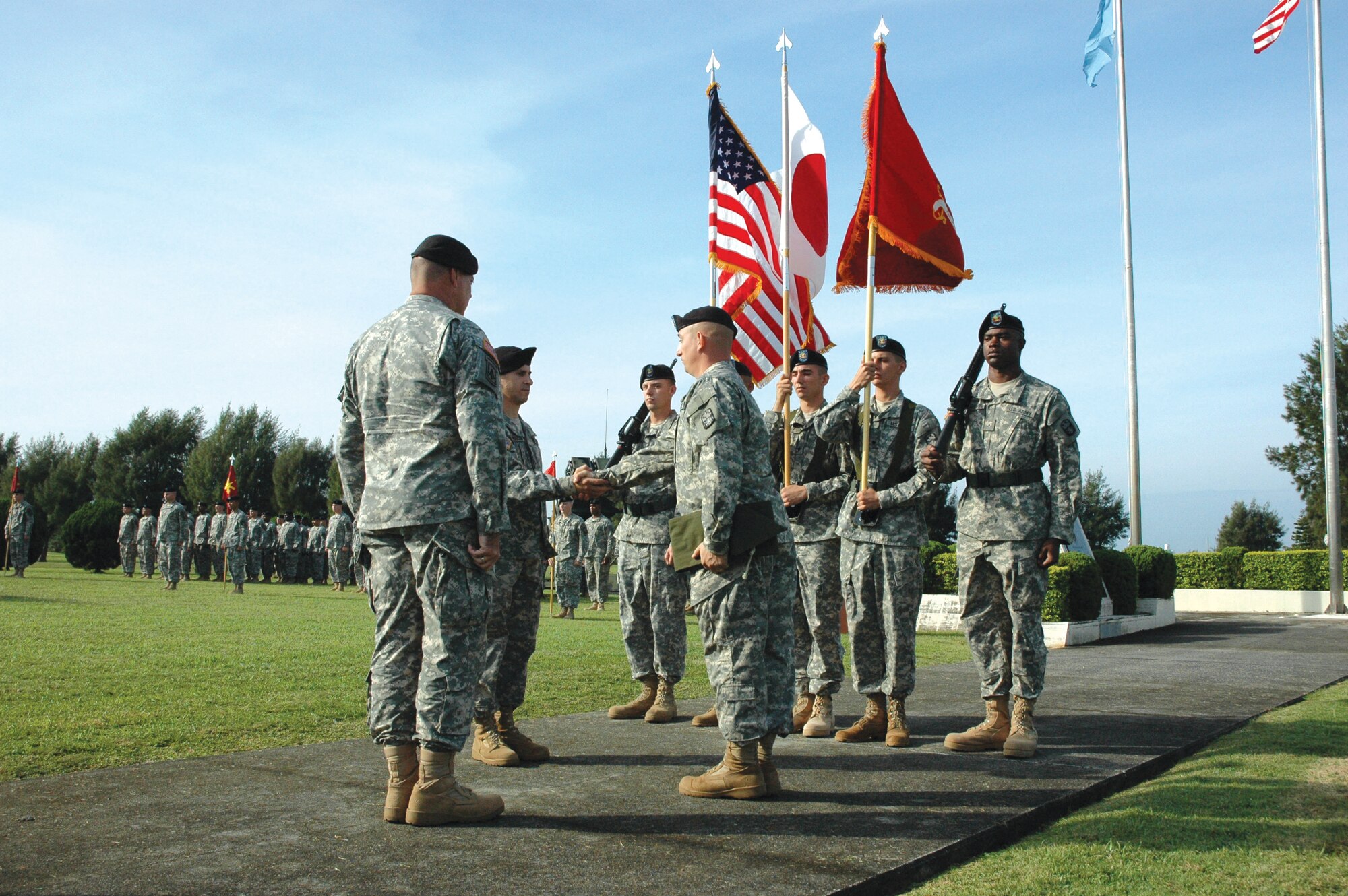 Army Brig. Gen. John Seward (left) oversees the activation of the 1-1 Air Defense Artillery Battalion as Army Lt. Col. Matthew Michaelson shakes hands with Army Command Sgt. Maj. Michael Kuppers during the official uncasing of the colors of the unit Nov. 29 at Kadena Air Base, Japan. General Seward is the 94th Army Air and Missile Defense Command commanding general, and Colonel Michaelson is the 1-1 ADA Battalion commander. (U.S. Air Force photo/Junko Kinjo)