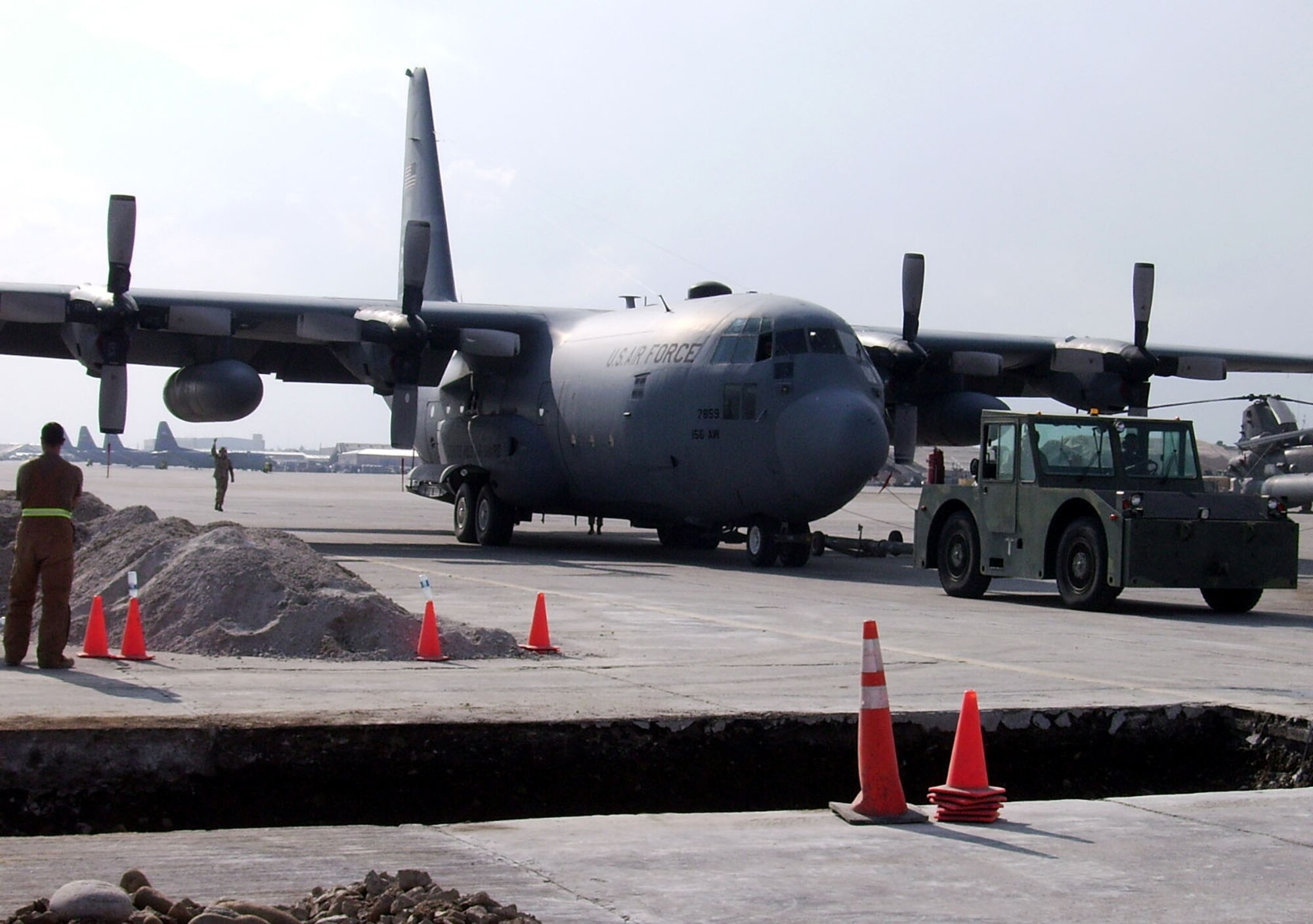 Airmen from the 455th Expeditionary Maintenance Group, tow a C-130 Hercules pass a construction project on the taxiway Nov. 18.  Airmen discovered a large sinkhole in the center of the taxiway and extended about 50 feet underneath the surface. It took Airmen from across the wing to work together to complete the project without interrupting the various missions on the flightline. (U.S. Air Force courtesy photo)